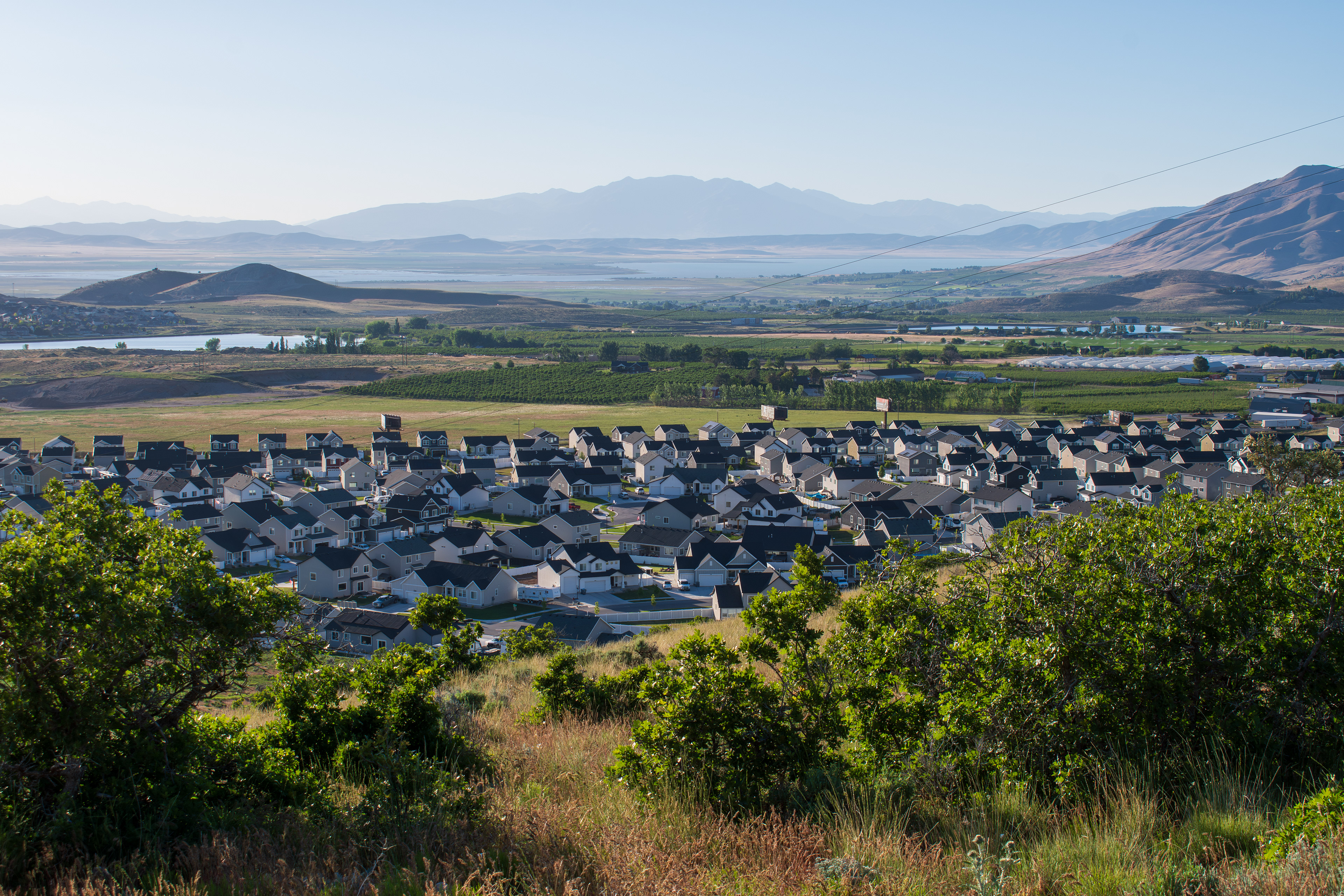 Santaquin, Utah – June 2, 2025: Wide view of a residential neighborhood with a mountainous backdrop and open valley under a clear sky.