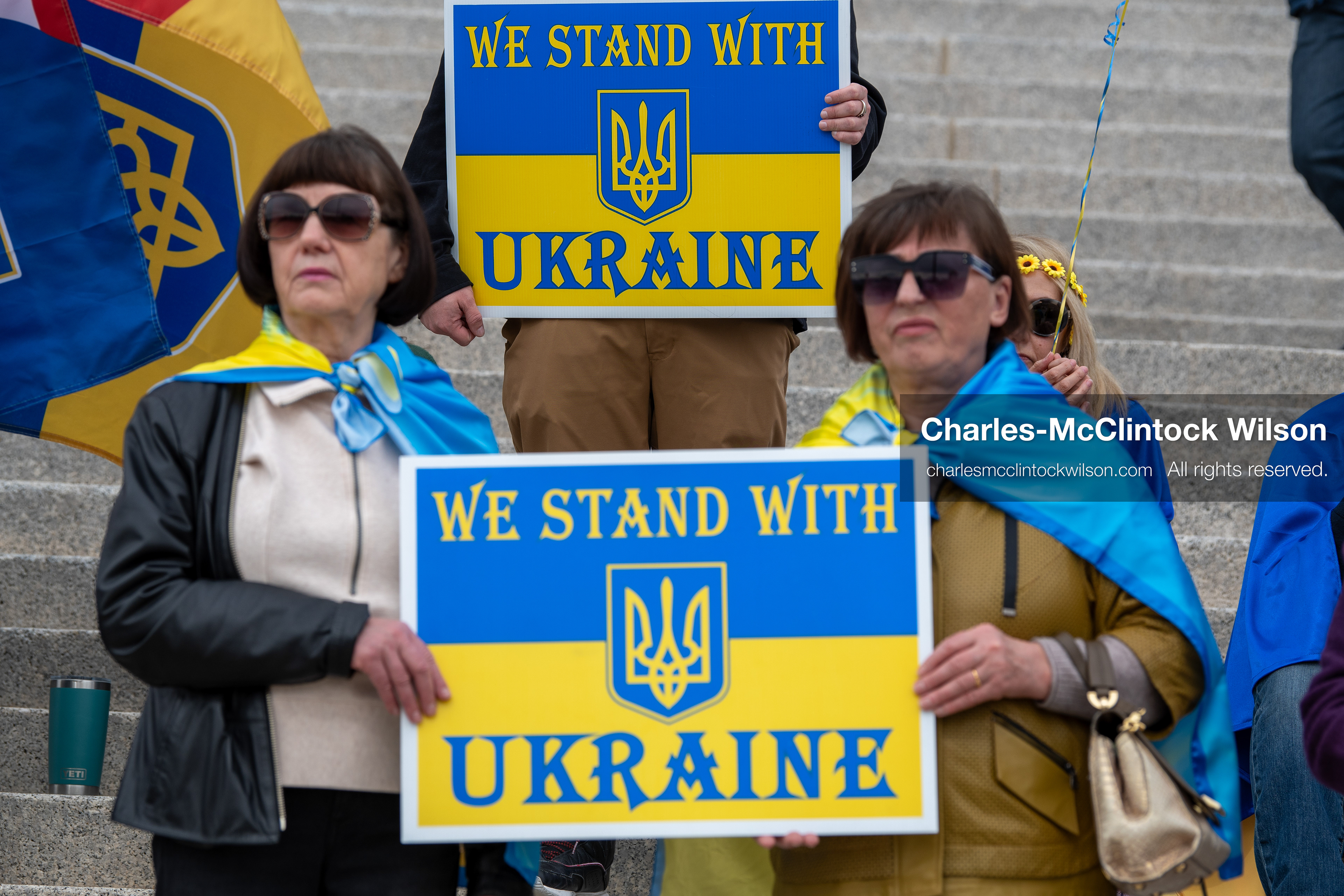  February 28, 2026, Salt Lake City, Utah, USA: Demonstrators hold signs reading We Stand With Ukraine while wrapped in the Ukrainian flag during the Stand With Ukraine rally at the Utah State Capitol. The gathering marked the four year anniversary of the full scale Russian invasion of Ukraine and brought community members together in support of Ukrainians and local humanitarian efforts. (Credit Image: © Charles McClintock Wilson/ZUMA Press Wire)