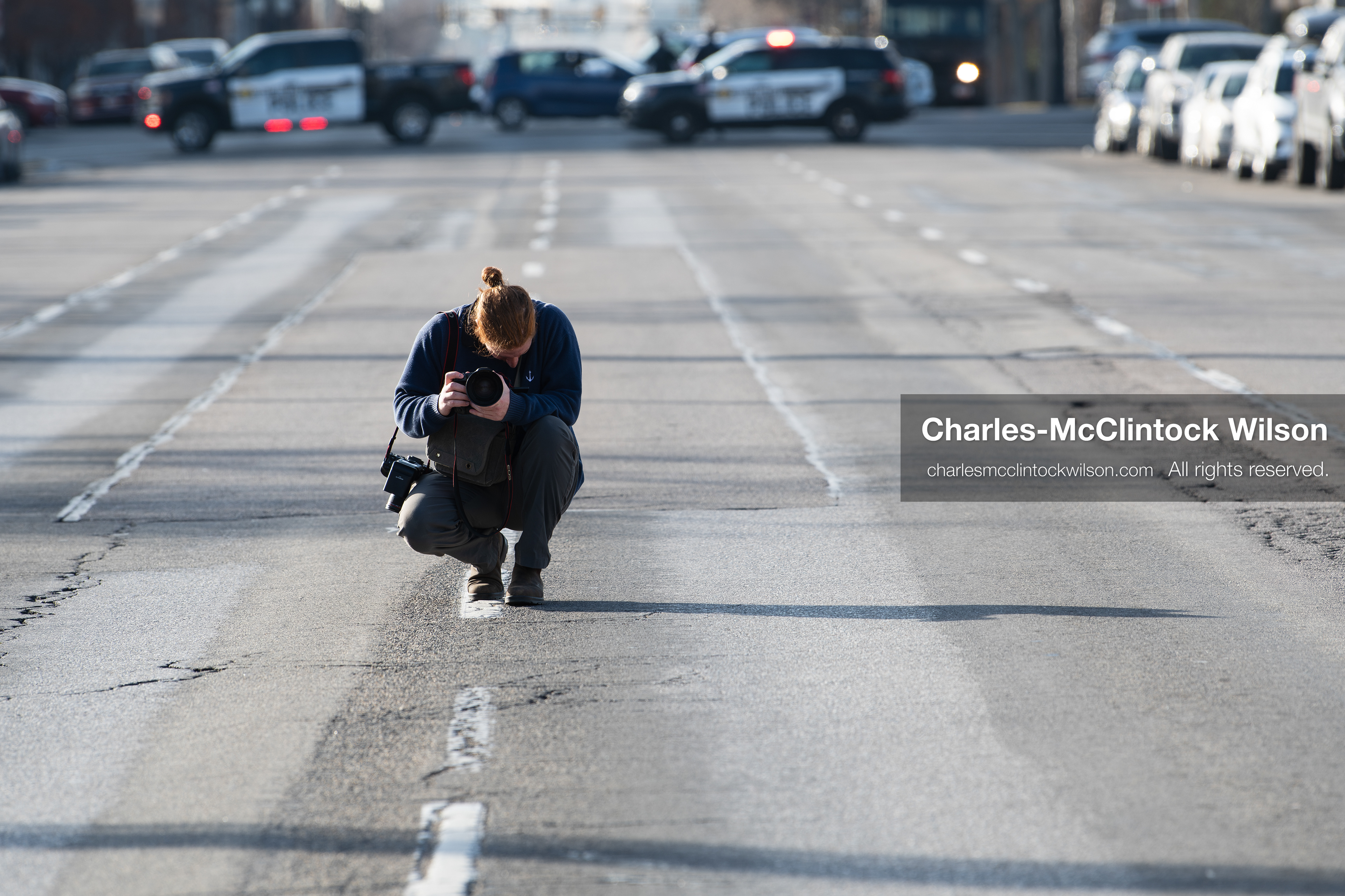 January 30, 2026, Salt Lake City, Utah, USA: A photographer crouches in the street as police vehicles block traffic during an anti‑ICE protest in Salt Lake City, part of a nationwide response to immigration enforcement policies. (Credit Image: © Charles‑McClintock Wilson/ZUMA Press Wire)