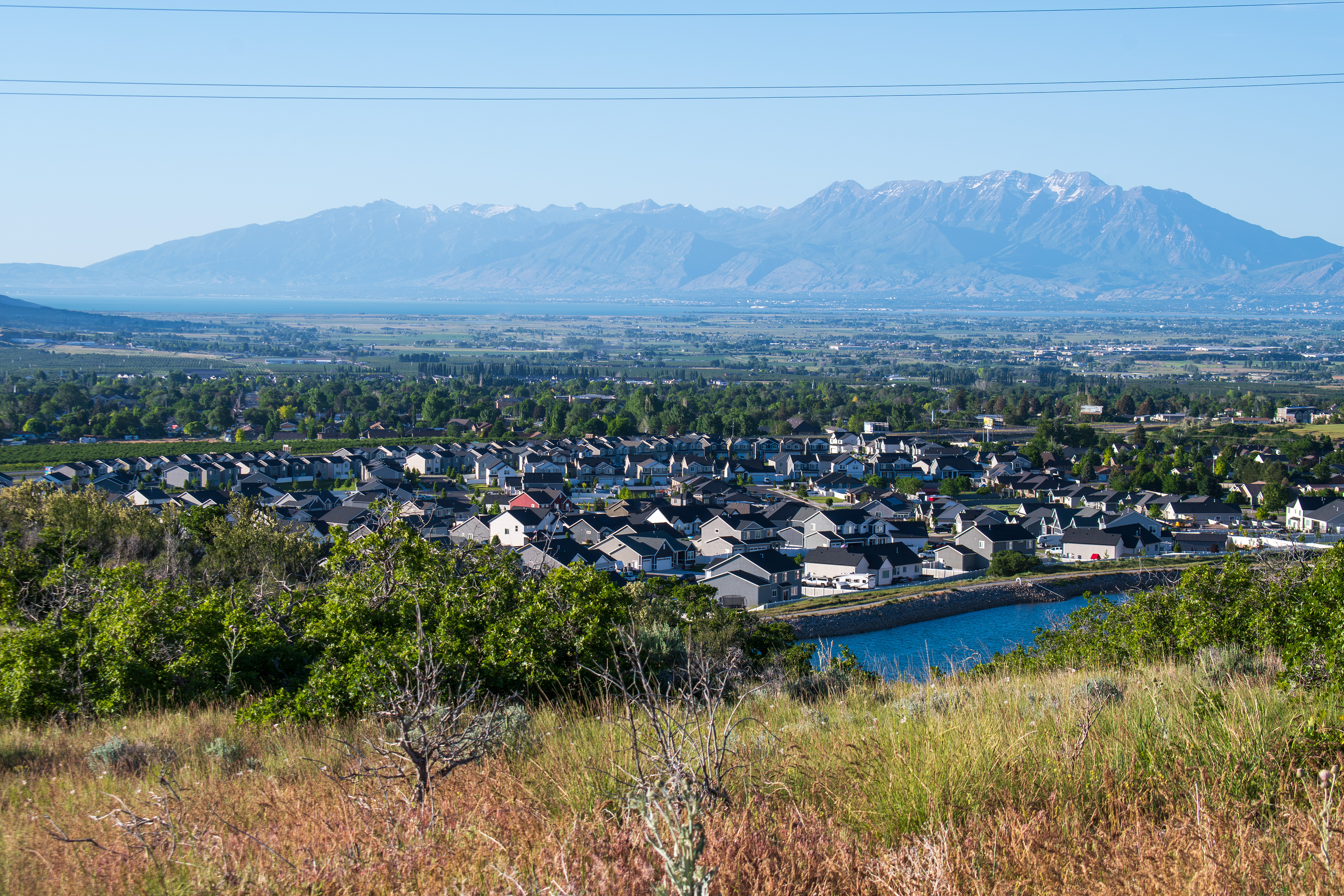 Santaquin, Utah – June 2, 2025: Wide view of a residential neighborhood with a mountainous backdrop and open valley under a clear sky.