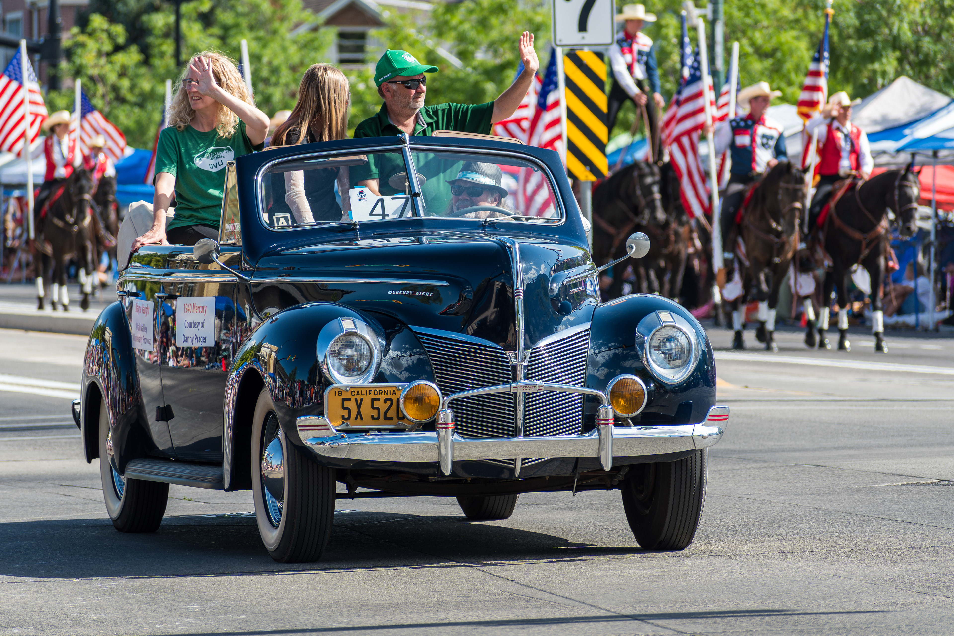 Provo, Utah – July 4, 2025: People ride and wave from a vintage convertible car during the Freedom Festival Grand Parade in downtown Provo.