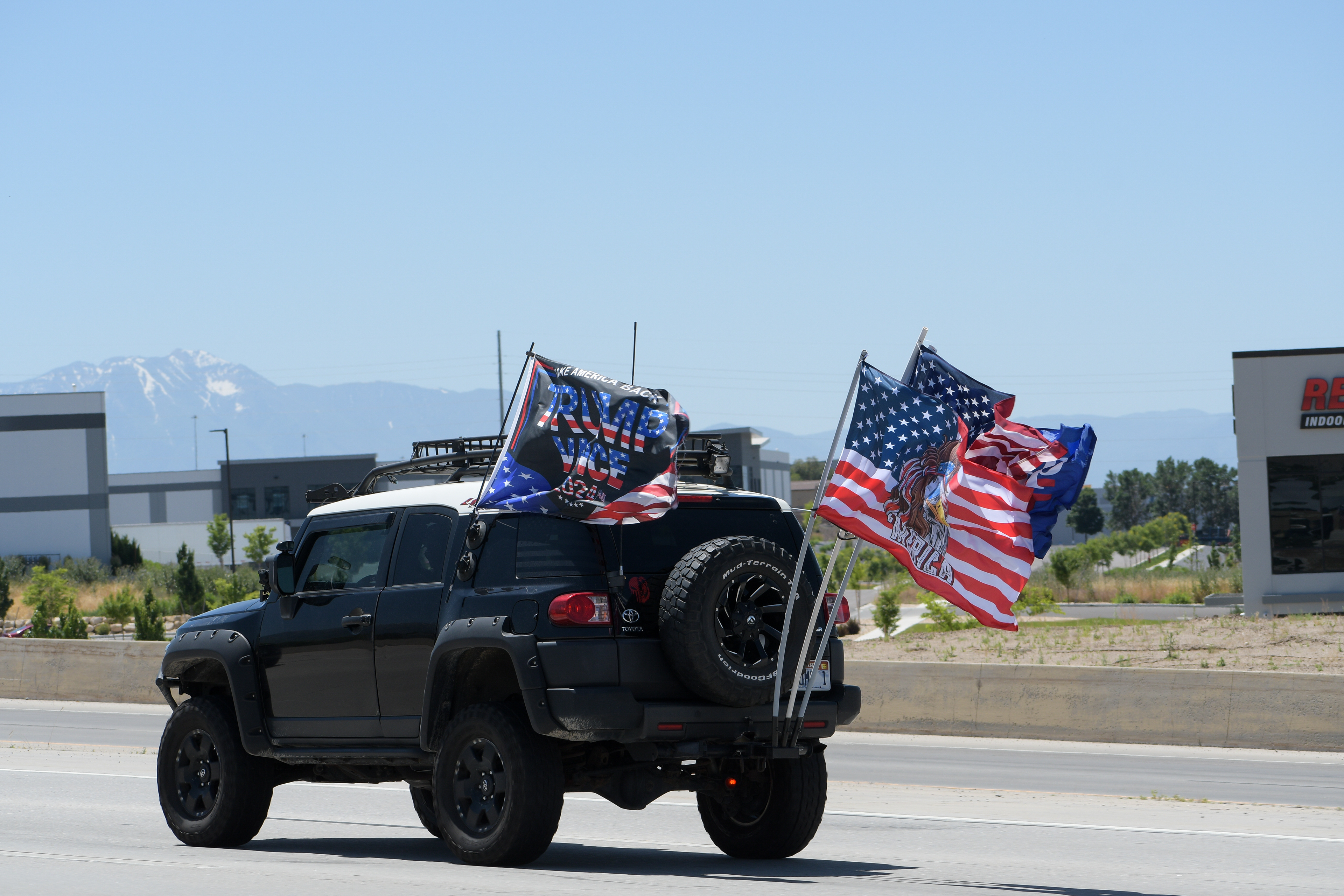 LEHI, UTAH – JUNE 17, 2025: Vehicles displaying flags in support of US President Donald Trump travel southbound on Interstate 15 in Lehi.