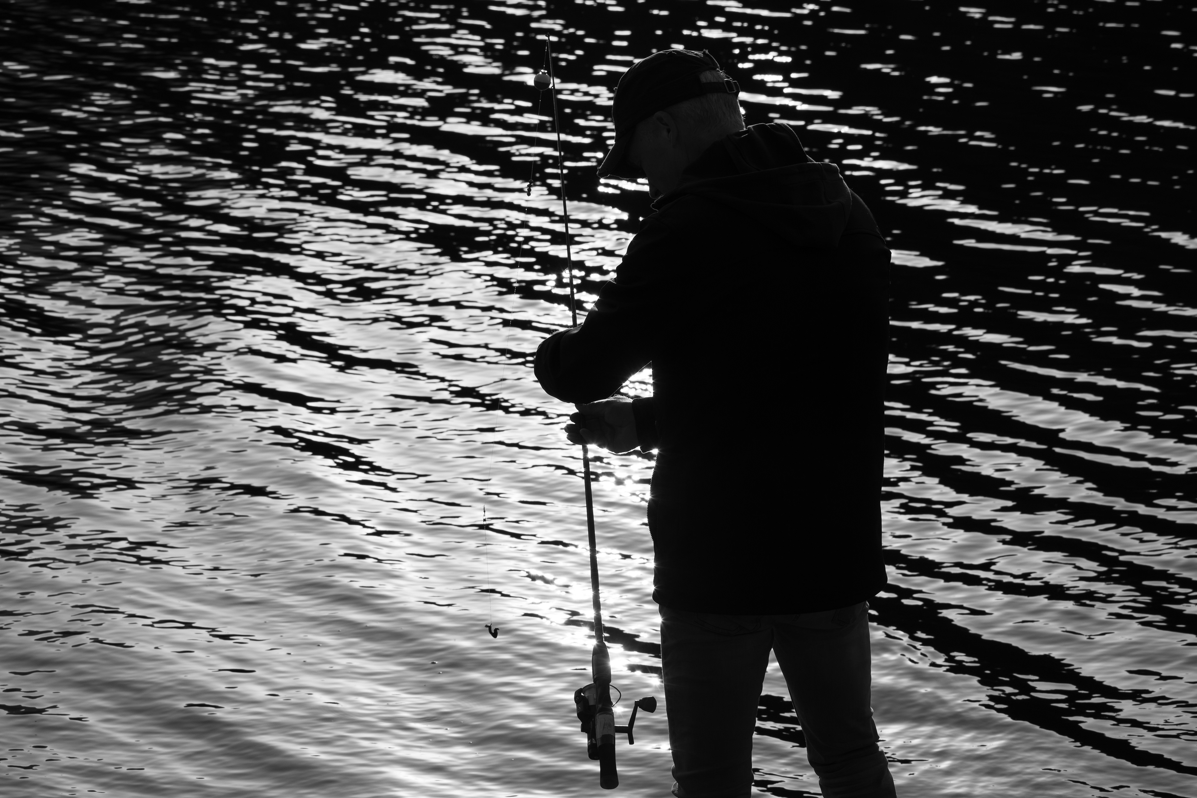 Summit County, Utah – July 20, 2025: A black and white image of a man fishing captures a quiet moment at Smith and Morehouse Reservoir.