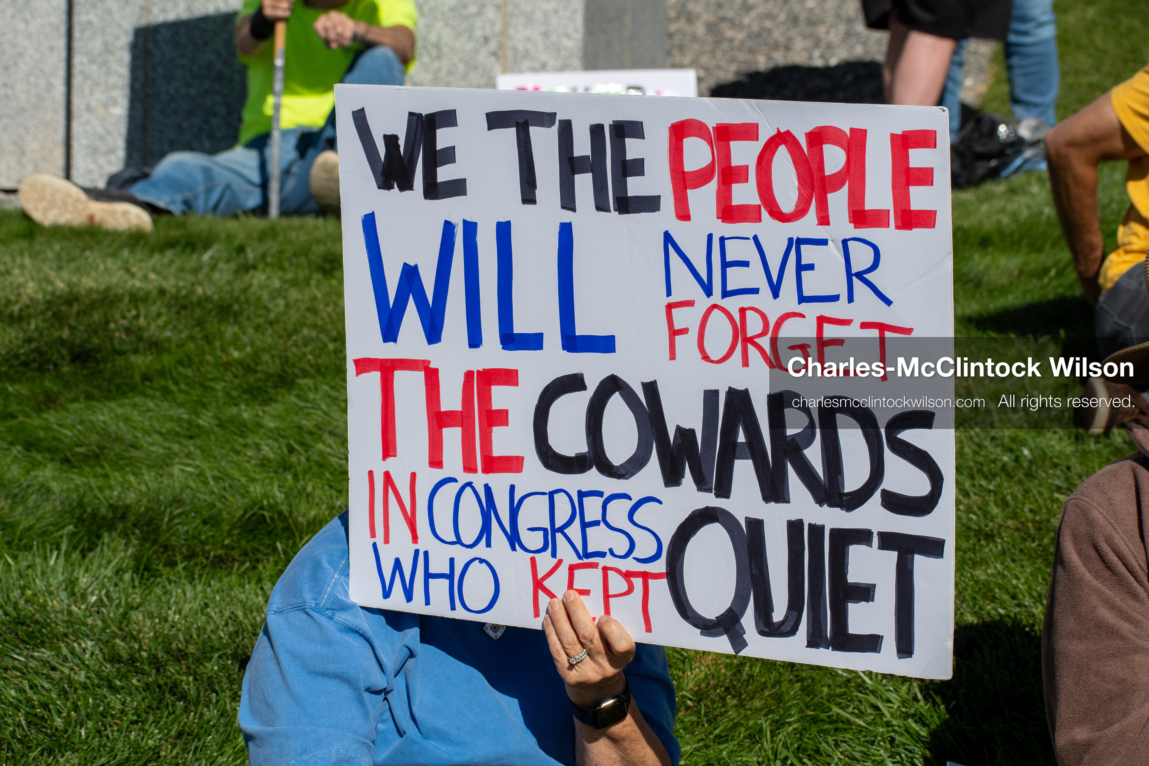 October 18, 2025, Salt Lake City, Utah, USA: A demonstrator raises a placard during a "No Kings" protest held at the Utah State Capitol. Other participants and signs are visible in the background during the public gathering.