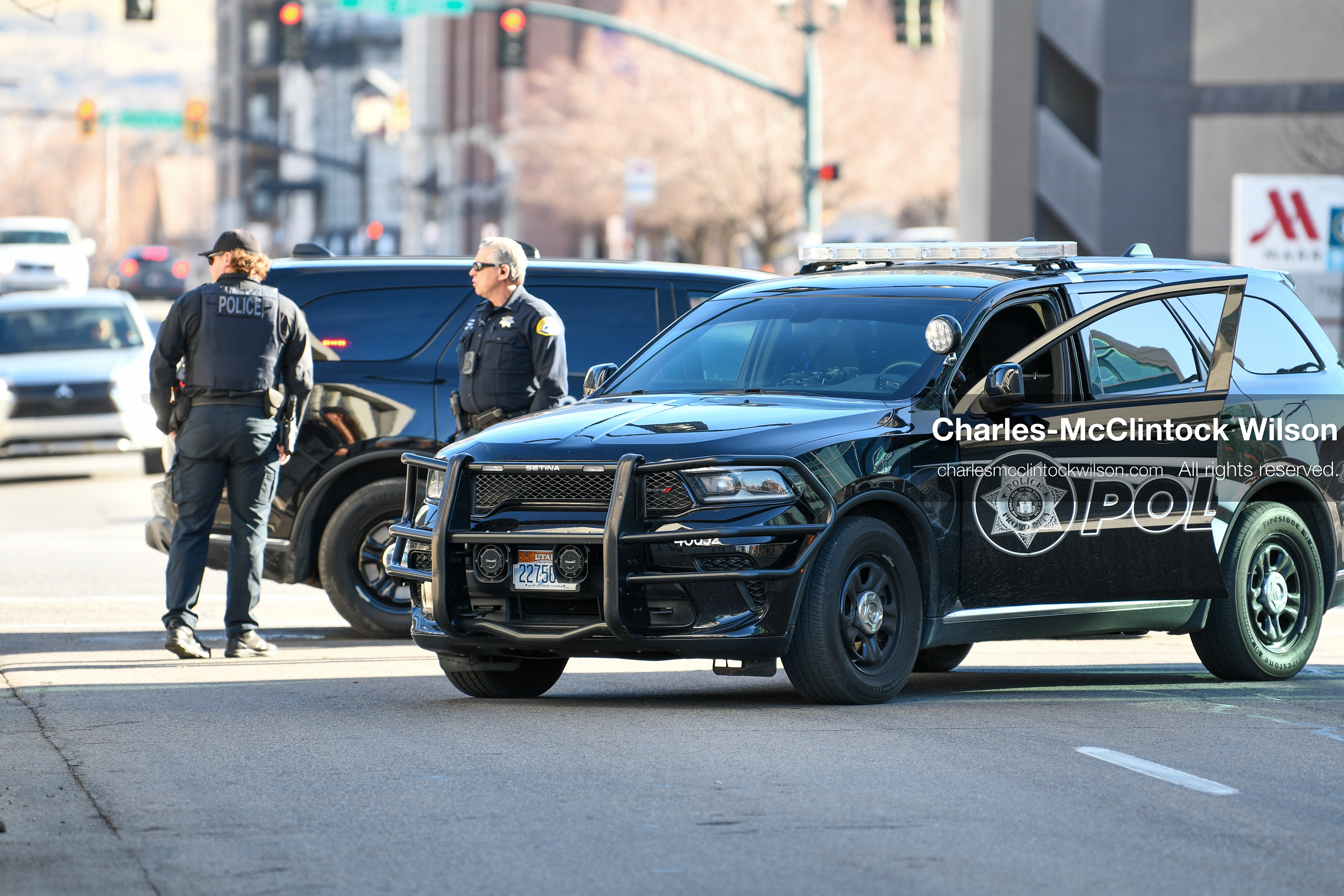 PROVO, UTAH, USA – DECEMBER 11, 2025: Two Provo Police officers block traffic near patrol vehicles outside the Fourth District Court in Provo during the first in‑person court appearance of Tyler Robinson in the Charlie Kirk murder case. (Credit Image: © Charles‑McClintock Wilson/ZUMA Press Wire)