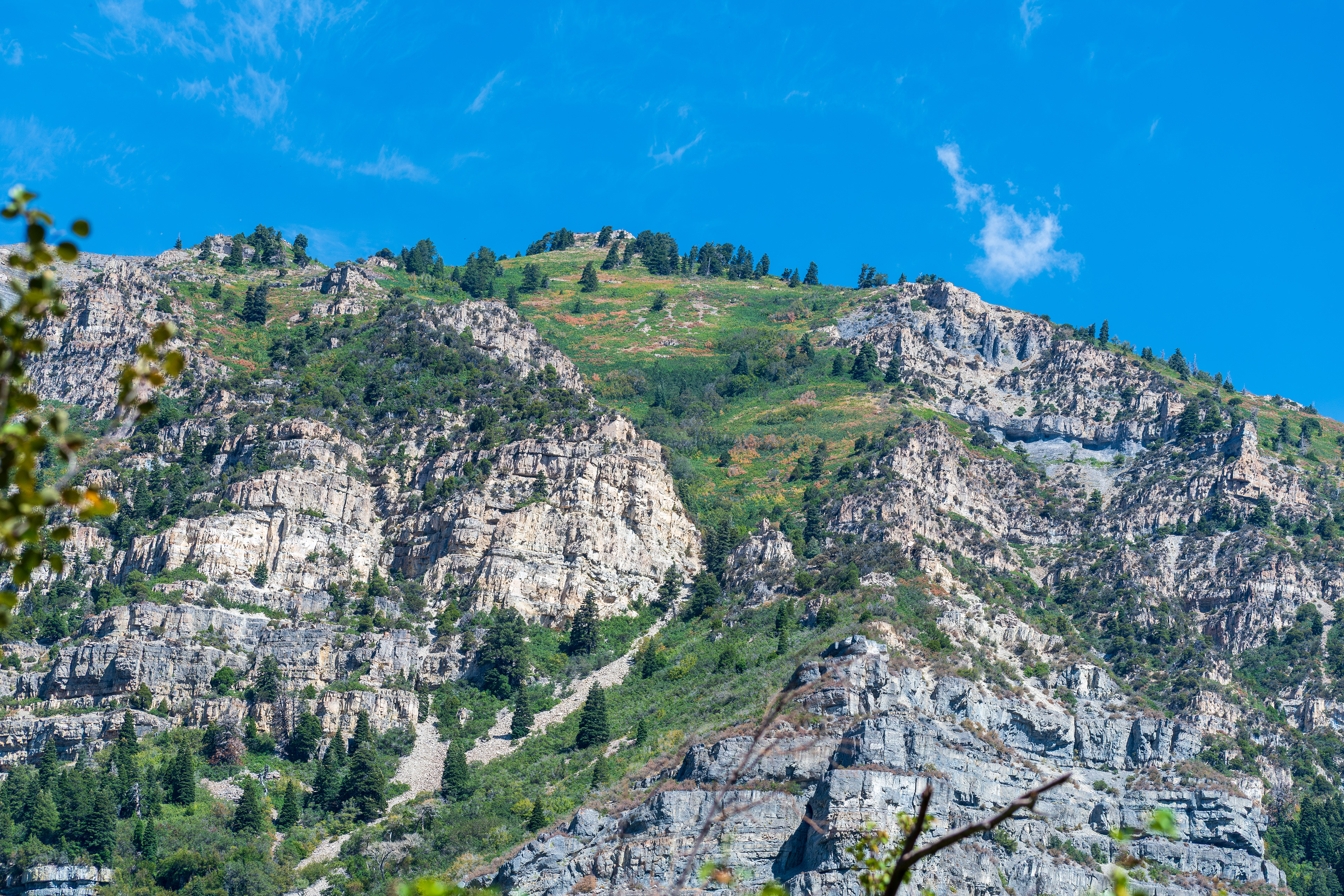 Provo Canyon, Utah, USA — September 1, 2025: A view from Bridal Veil Falls captures steep rocky cliffs and scattered vegetation under clear blue skies.