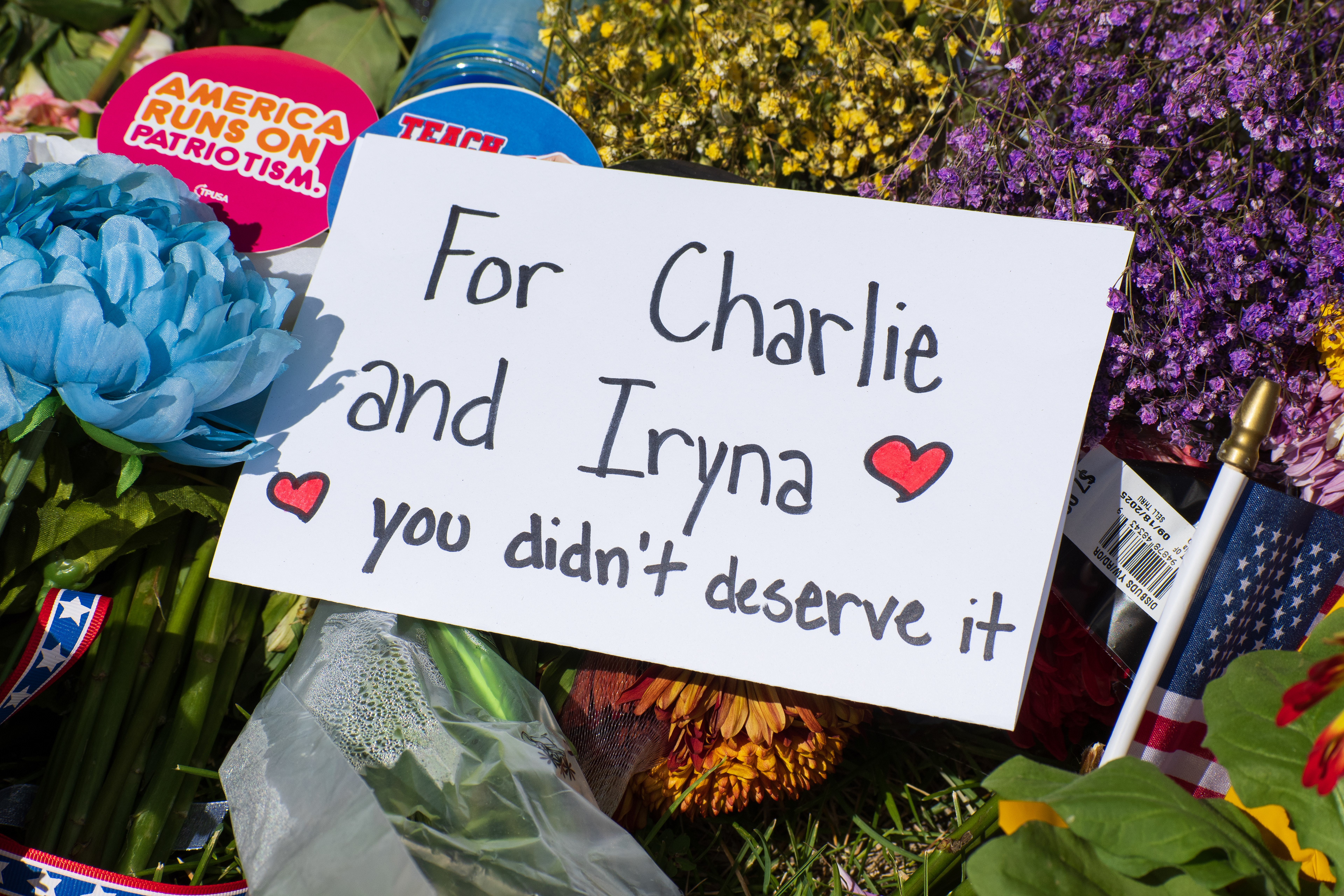 OREM, UTAH – SEPTEMBER 12, 2025: A handwritten sign reading “For Charlie and Iryna — you didn’t deserve it” is placed among flowers, an American flag, and personal items at a memorial site near Utah Valley University. The tribute reflects a dual gesture of remembrance and public mourning. © Charles‑McClintock Wilson / ZUMA Press