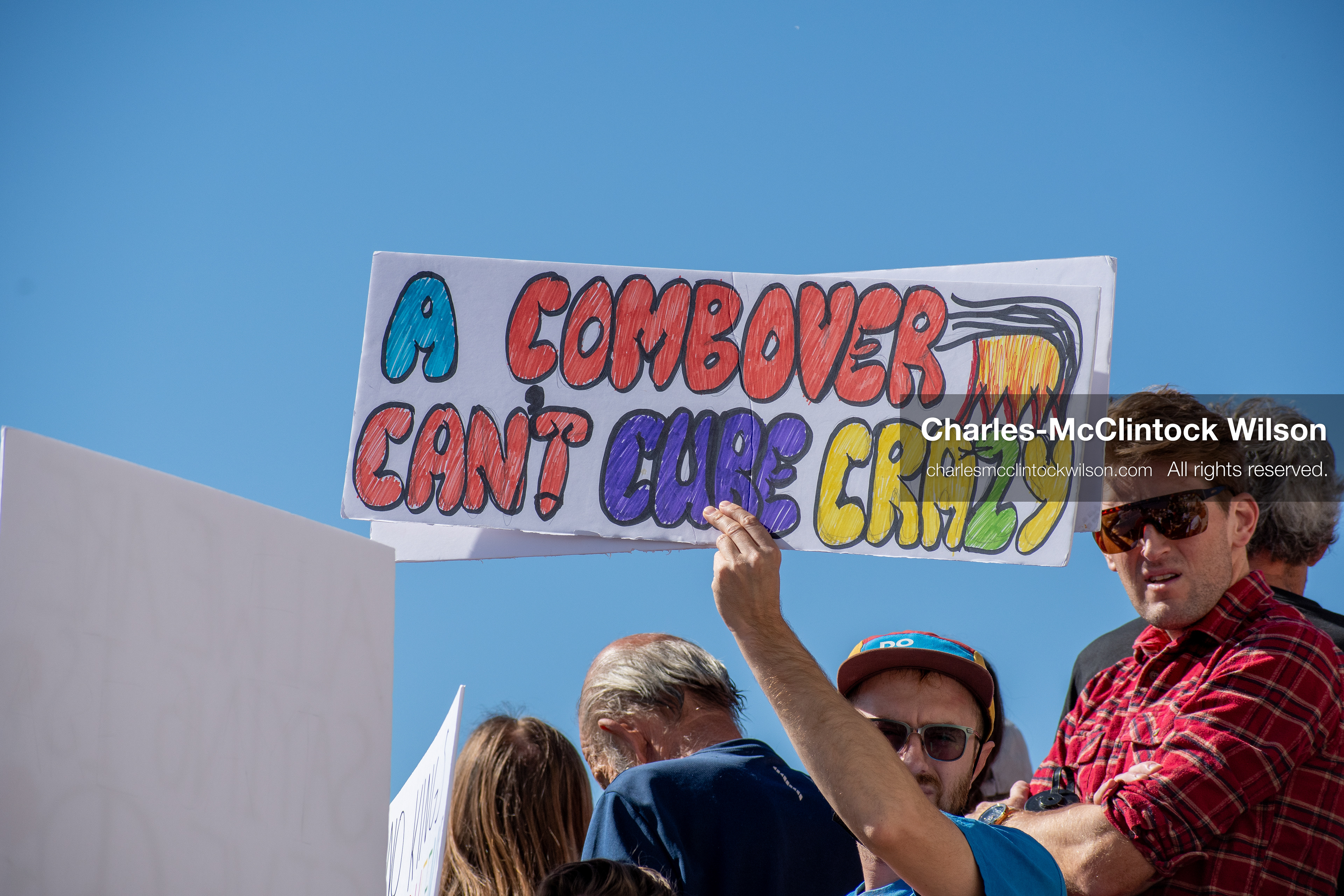 October 18, 2025, Salt Lake City, Utah, USA: A demonstrator raises a placard during a "No Kings" protest held at the Utah State Capitol. Other participants and signs are visible in the background during the public gathering.