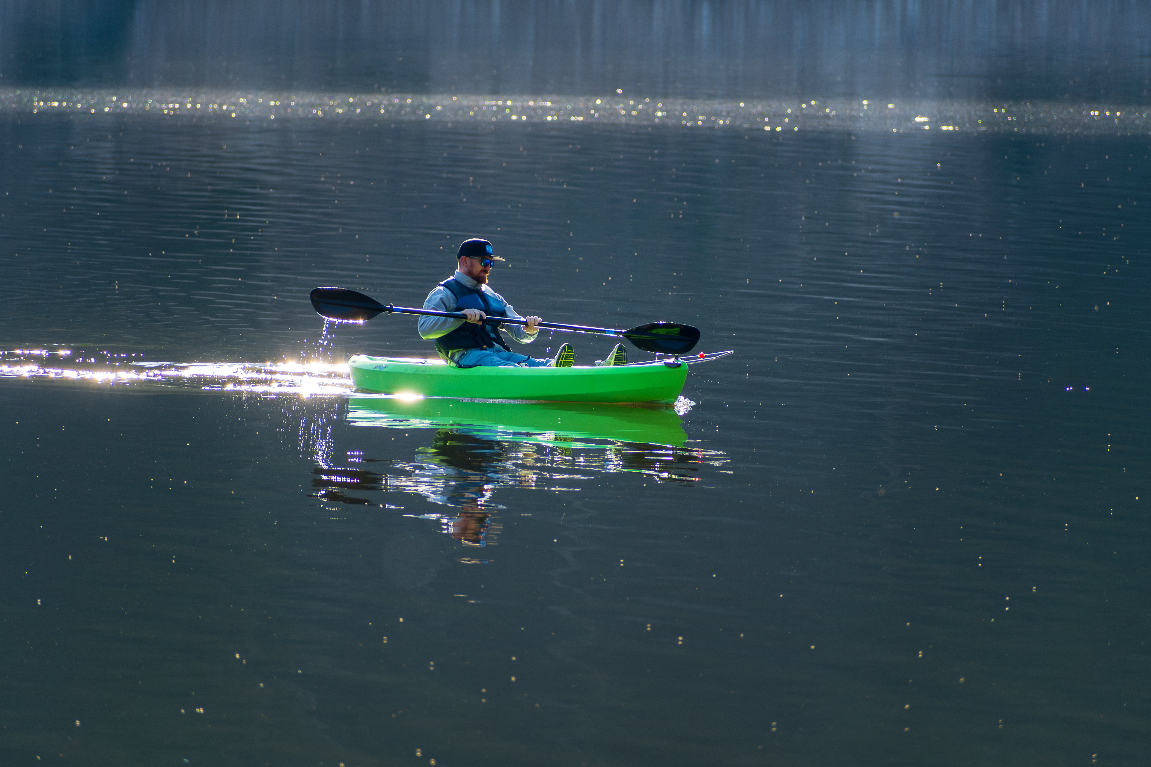 Summit County, Utah – July 20, 2025: A man paddles a bright green kayak while fishing at Smith and Morehouse Reservoir.