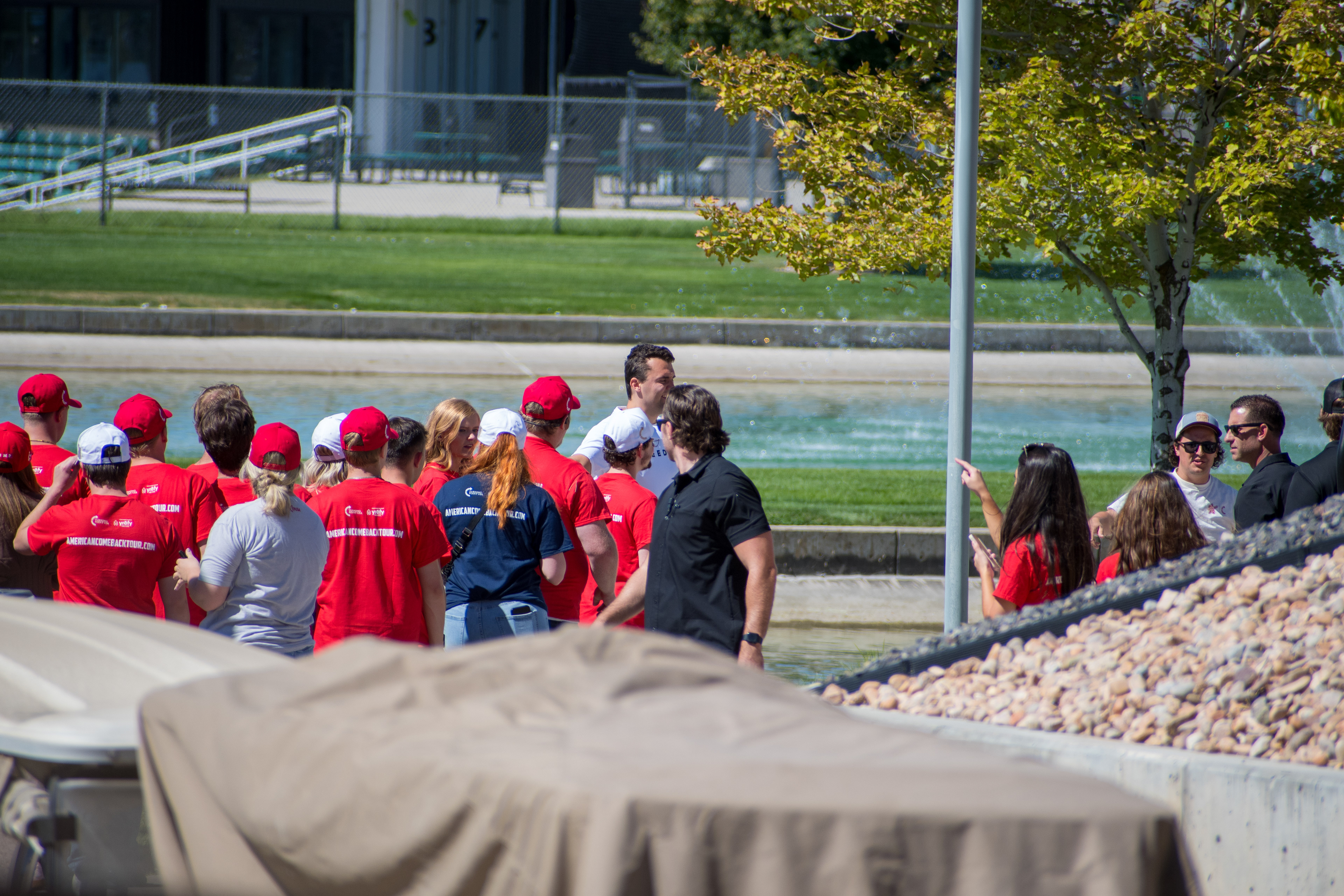 OREM, UTAH – SEPTEMBER 10, 2025: Supporters gather near a water feature ahead of Charlie Kirk’s public appearance at Utah Valley University. Wearing red shirts and hats bearing political slogans, attendees stand near event infrastructure and vehicles in anticipation of Kirk’s arrival. The image reflects the branding, energy, and grassroots mobilization that shaped the atmosphere leading into his final public engagement. © Charles-McClintock Wilson / ZUMA Press