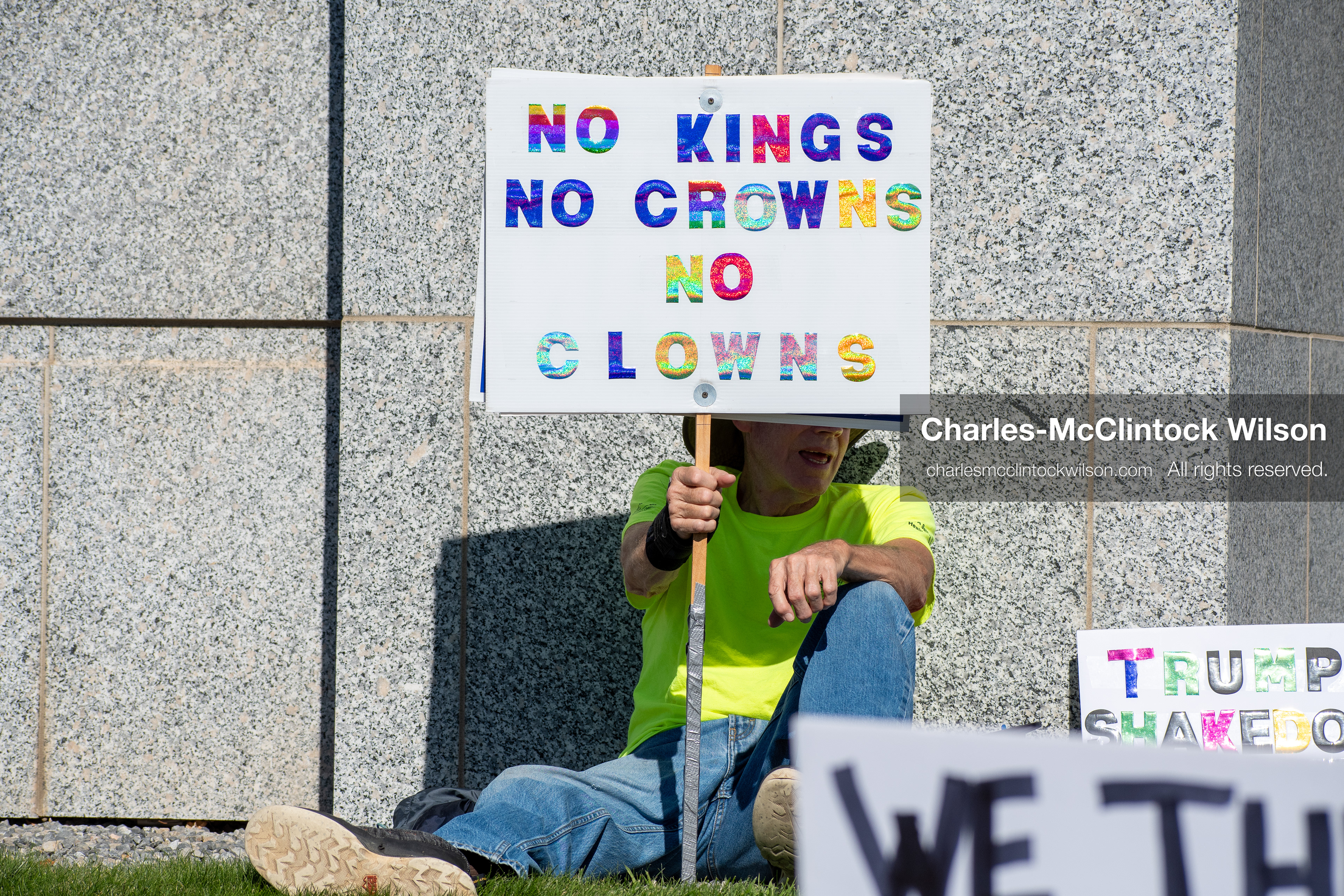 October 18, 2025, Salt Lake City, Utah, USA: A demonstrator raises a placard during a "No Kings" protest held at the Utah State Capitol. Other participants and signs are visible in the background during the public gathering.
