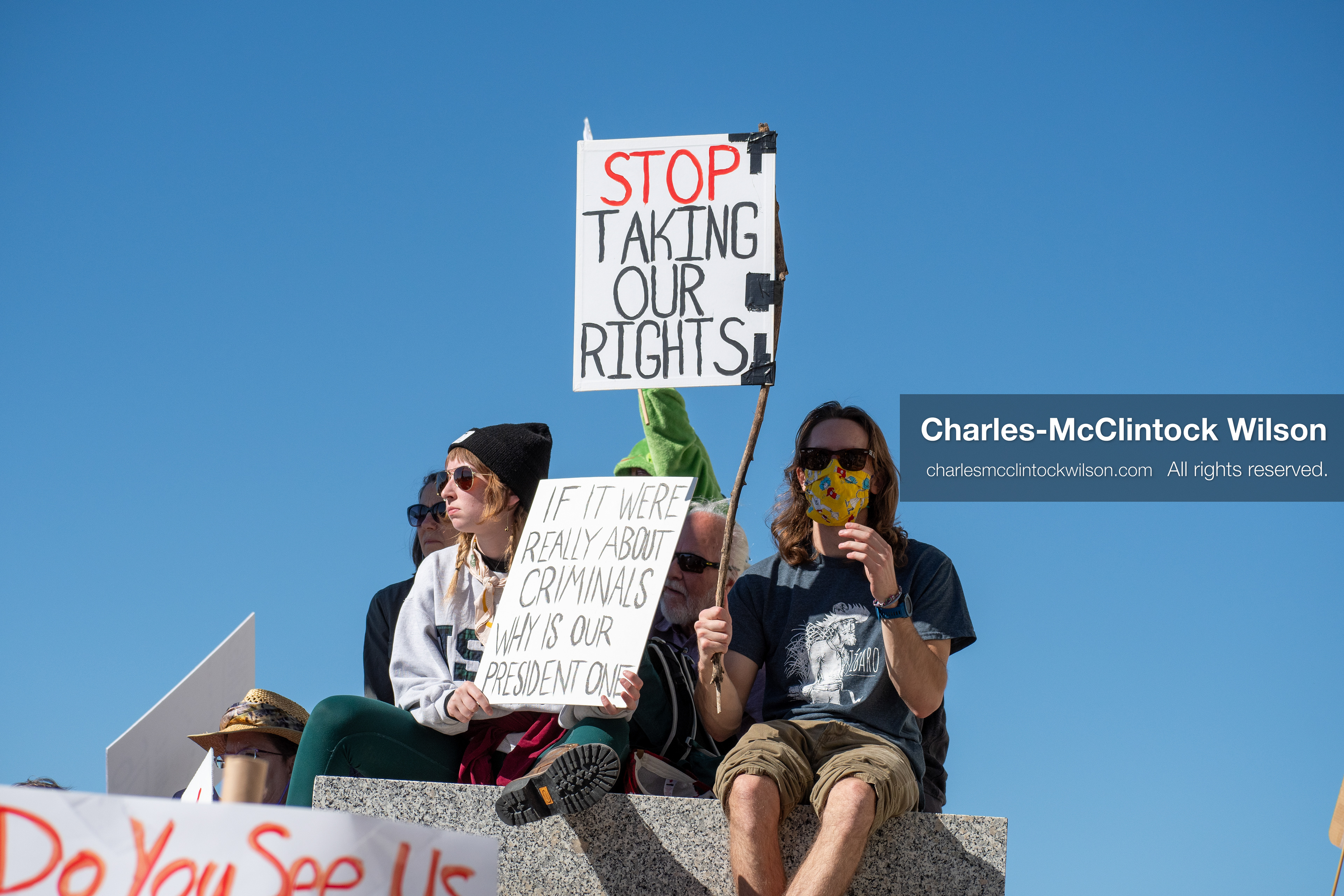 October 18, 2025, Salt Lake City, Utah, USA: Demonstrators sit on a stone ledge during a "No Kings" protest at the Utah State Capitol. The protest was part of a nationwide mobilization.