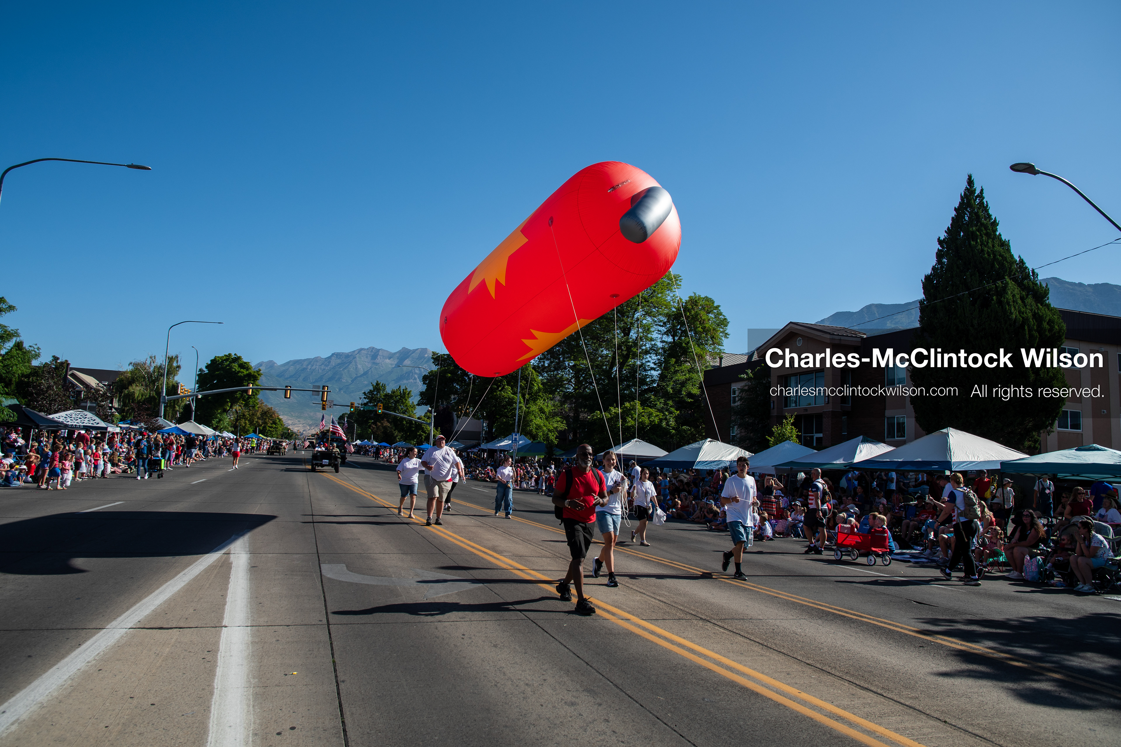 July 4, 2026, Provo, Utah, USA: Handlers guide a large, orange capsule-shaped helium balloon down the street past crowds during America's Freedom Festival Grand Parade in Provo, Utah, Saturday, July 4, 2026. The annual Independence Day event features expanded programming to honor the 250th anniversary of United States independence. (Credit Image: © Charles-McClintock Wilson/ZUMA Press Wire)