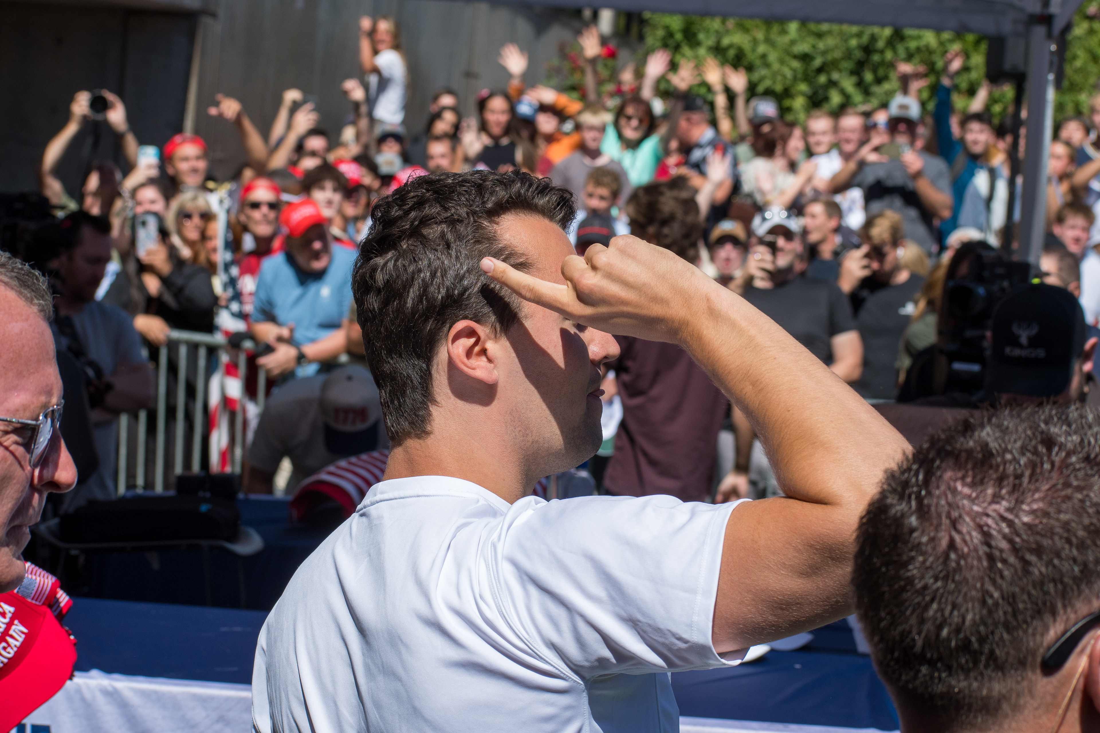 Charlie Kirk stands before a crowd of supporters during a public event at Utah Valley University. Separated by metal barricades, attendees raise phones and cheer as Kirk addresses them in one of his final public moments. The image reflects the intensity of civic engagement and the charged atmosphere that defined the gathering. © Charles-McClintock Wilson / ZUMA Press