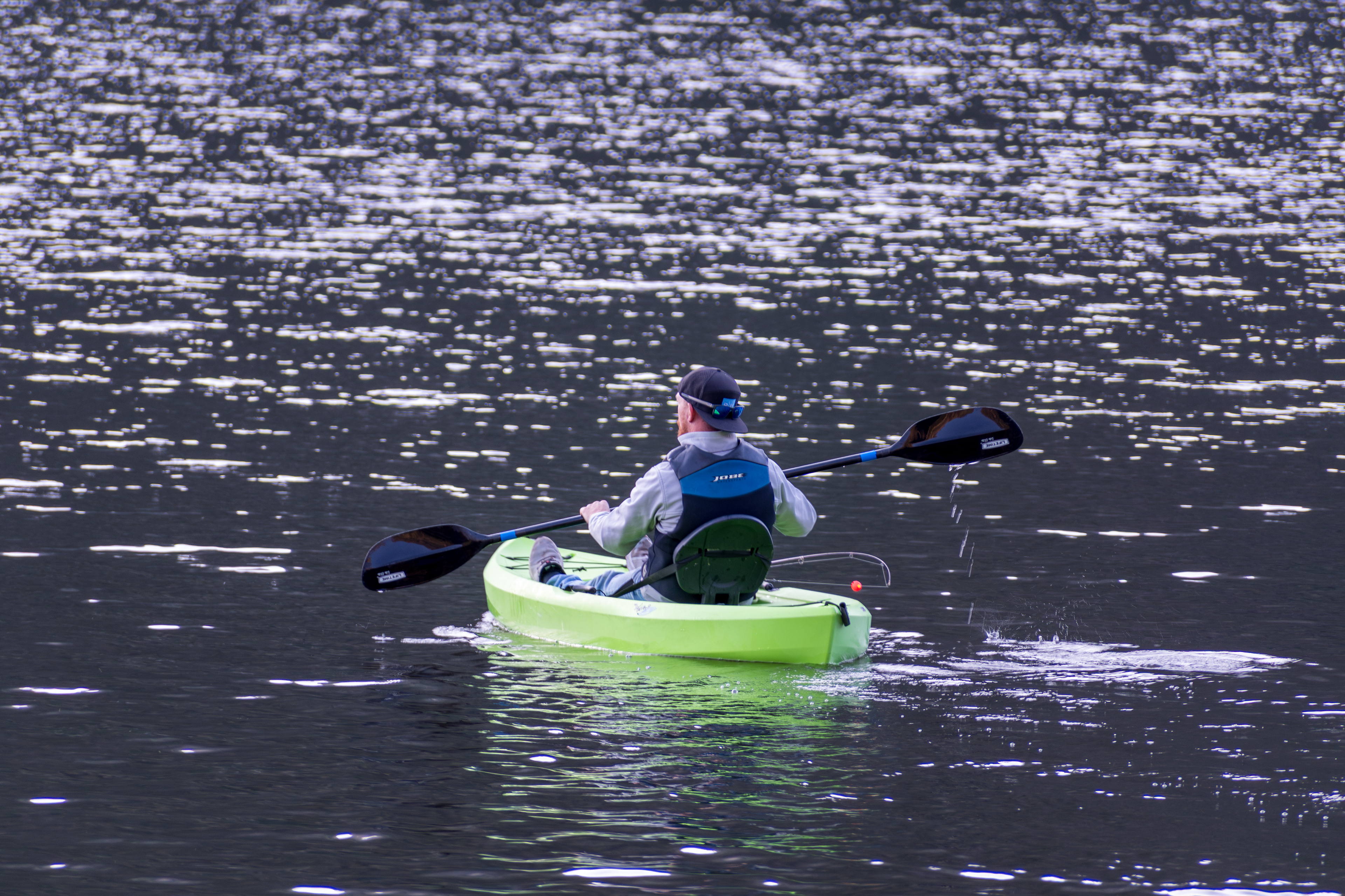 Summit County, Utah – July 20, 2025: A man paddles a bright green kayak while fishing at Smith and Morehouse Reservoir.