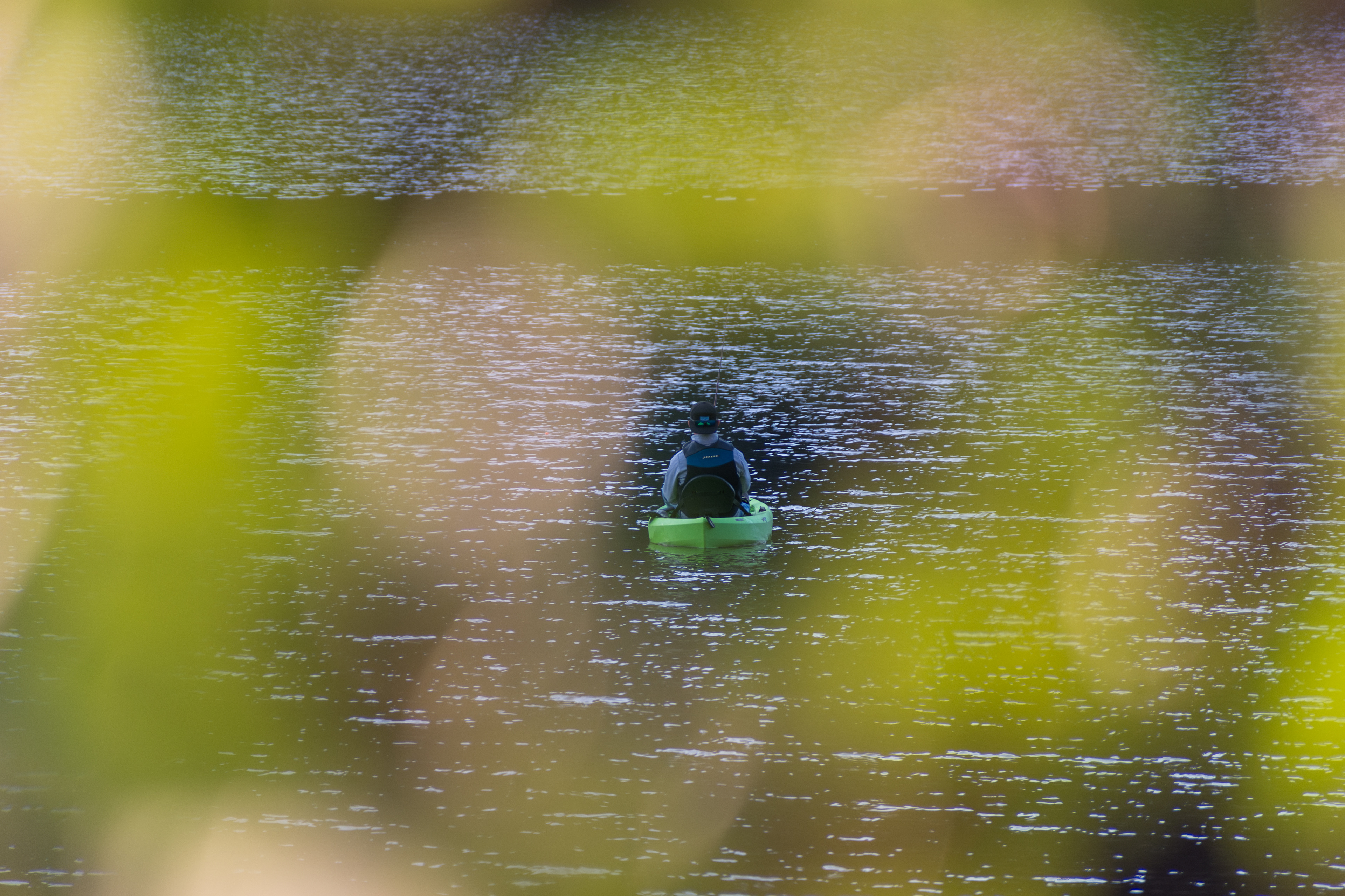 Summit County, Utah – July 20, 2025: Framed by soft foliage, a man quietly casts his line from a kayak in the middle of Smith and Morehouse Reservoir.