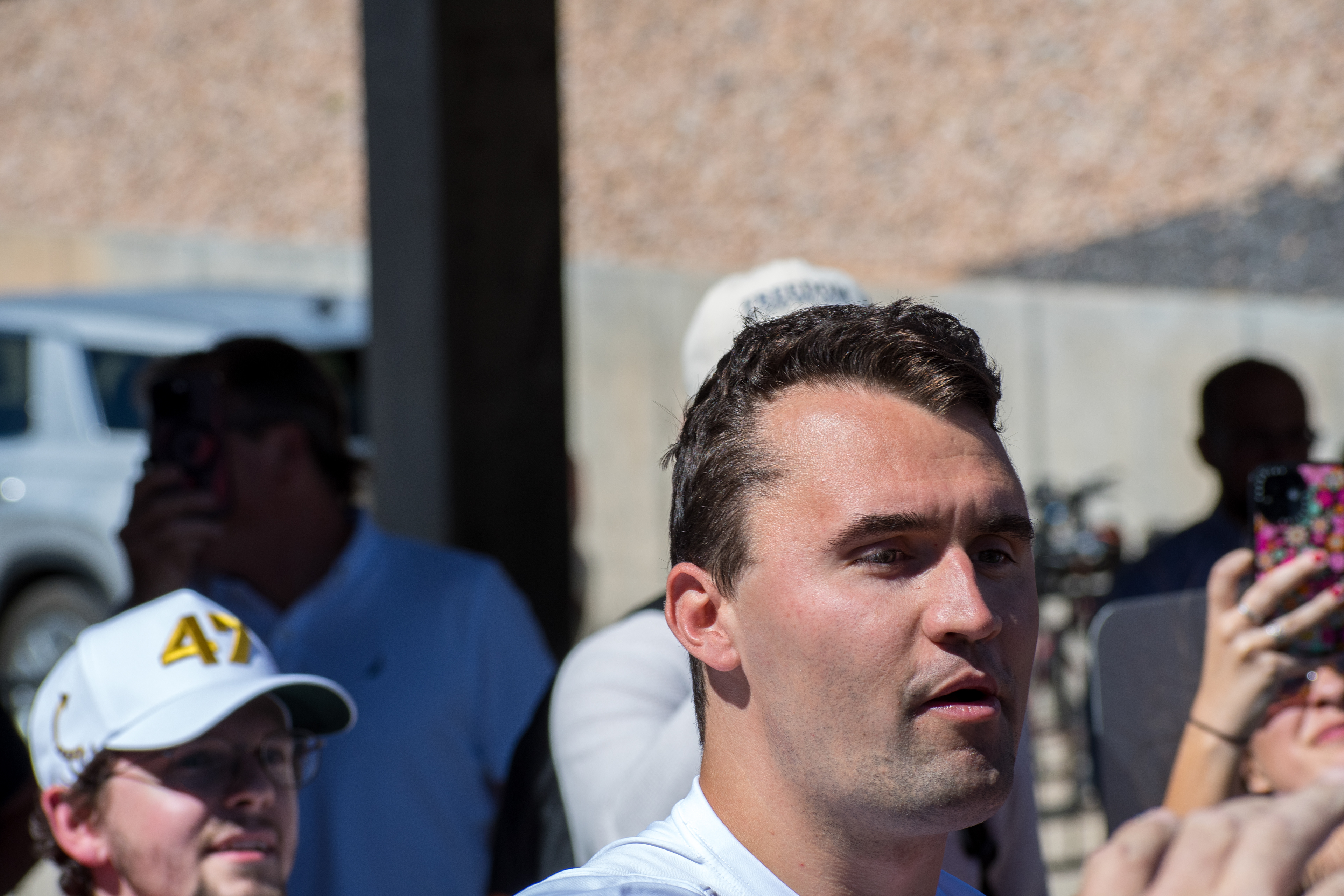 OREM, UTAH – SEPTEMBER 10, 2025: Charlie Kirk holds several “Make America Great Again” hats while interacting with supporters during a public event at Utah Valley University. Positioned near a merchandise table and surrounded by attendees, Kirk engages directly with the crowd in one of his final public moments. The image reflects the branding, outreach, and political symbolism that defined the gathering. © Charles-McClintock Wilson / ZUMA Press