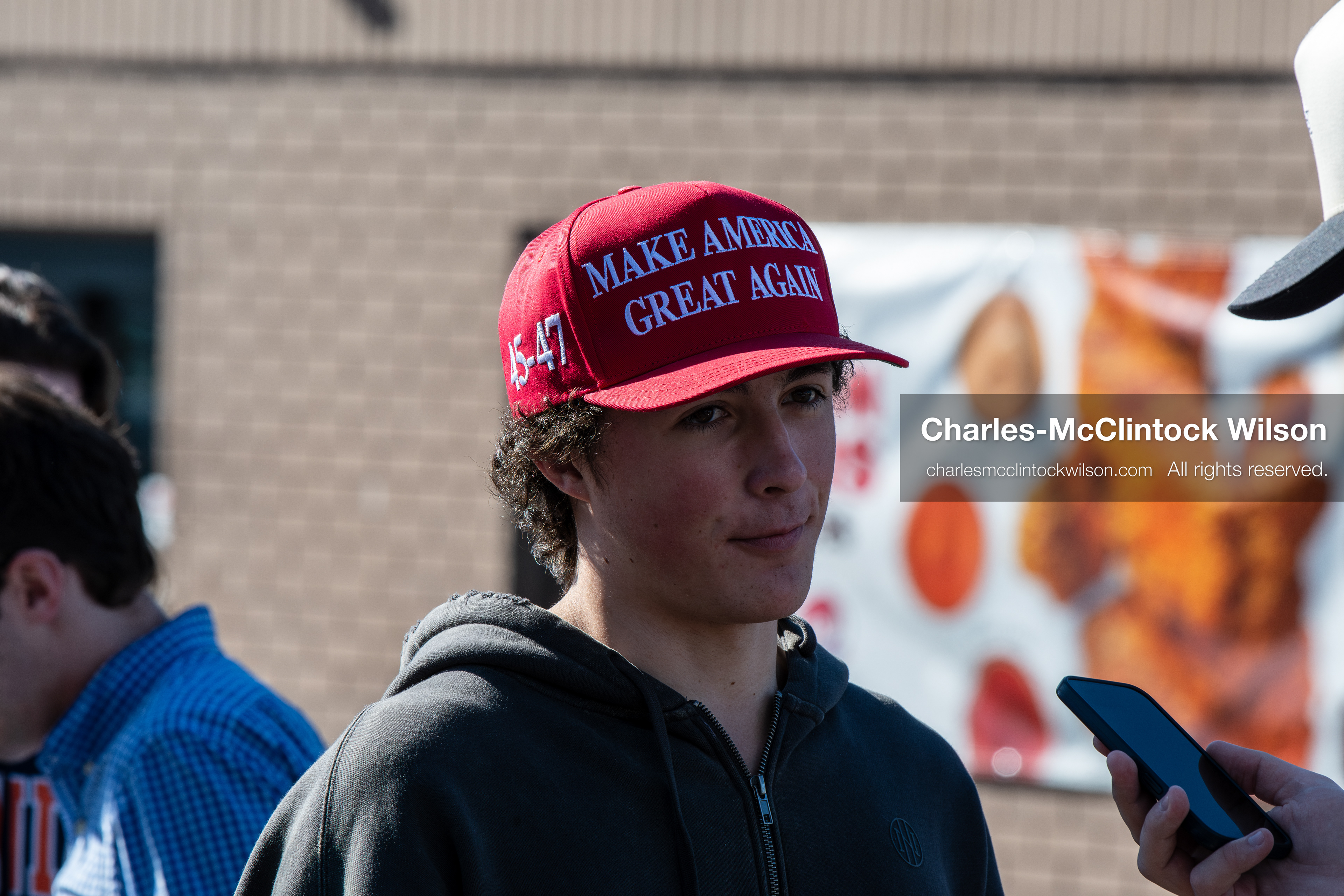 February 5, 2026, Provo, Utah, USA: A person wearing a red Make America Great Again hat is interviewed by another individual outside a business near Brigham Young University in Provo during a gathering opposing the presence of US Customs and Border Protection recruiters at a career fair held on the BYU campus. (Credit Image: © Charles McClintock Wilson/ZUMA Press Wire)