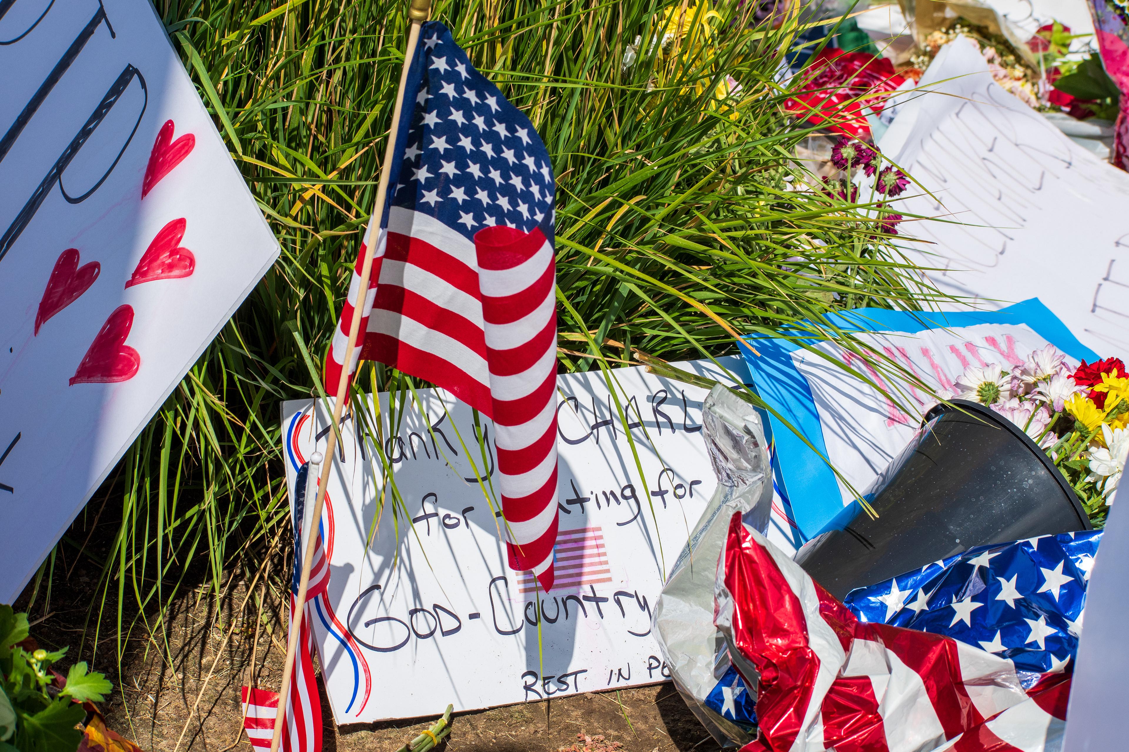 OREM, UTAH – SEPTEMBER 12, 2025: American flags, flowers, candles, and personal tributes are arranged at a memorial site for Charlie Kirk outside Timpanogos Regional Hospital. The display includes patriotic symbols and decorative items placed on the grass near the roadside. © Charles‑McClintock Wilson / ZUMA Press