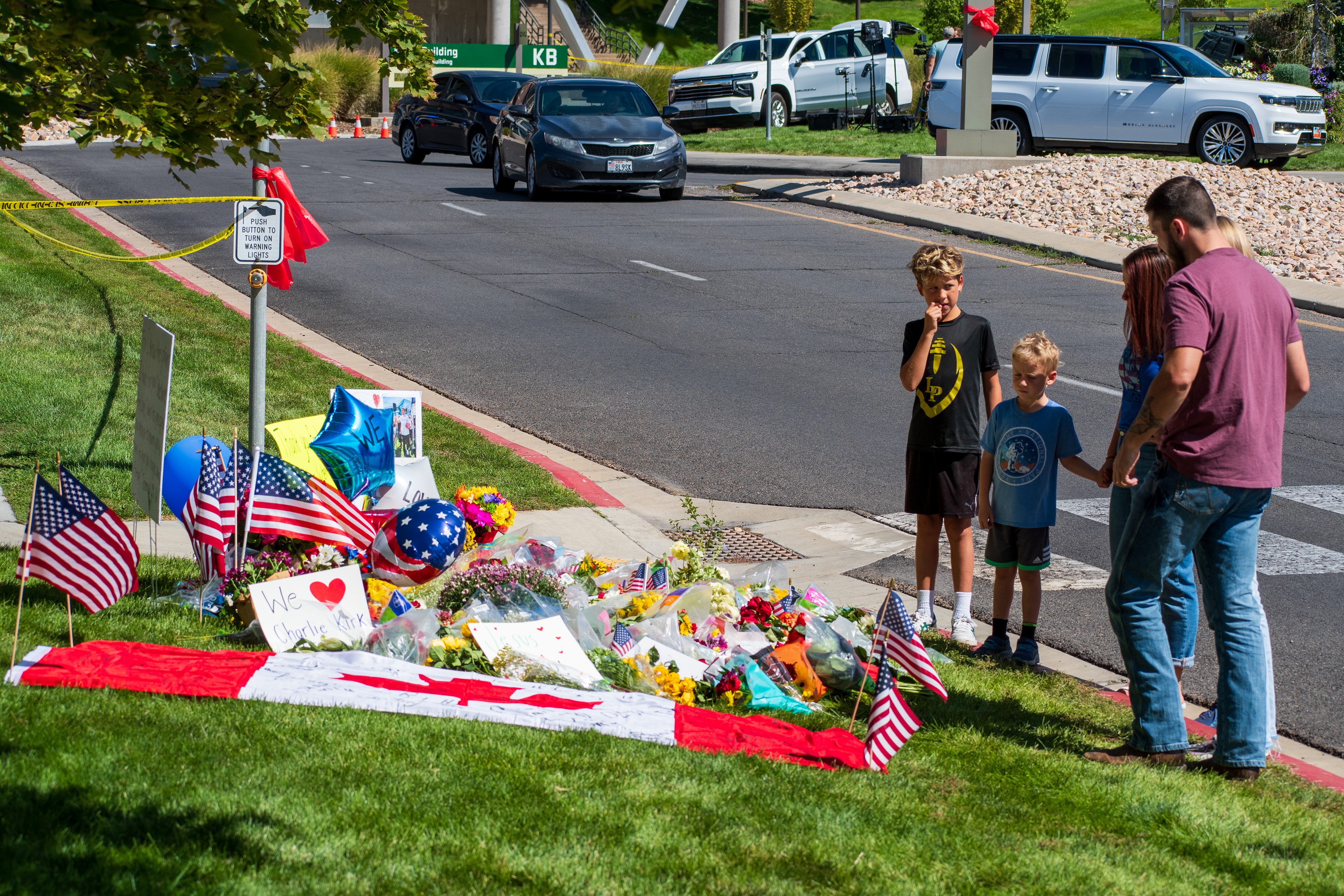 OREM, UTAH – SEPTEMBER 12, 2025: Families gather at a memorial site for Charlie Kirk on the campus of Utah Valley University. The tribute includes American flags, balloons, flowers, and handwritten posters arranged near a building entrance. © Charles‑McClintock Wilson / ZUMA Press