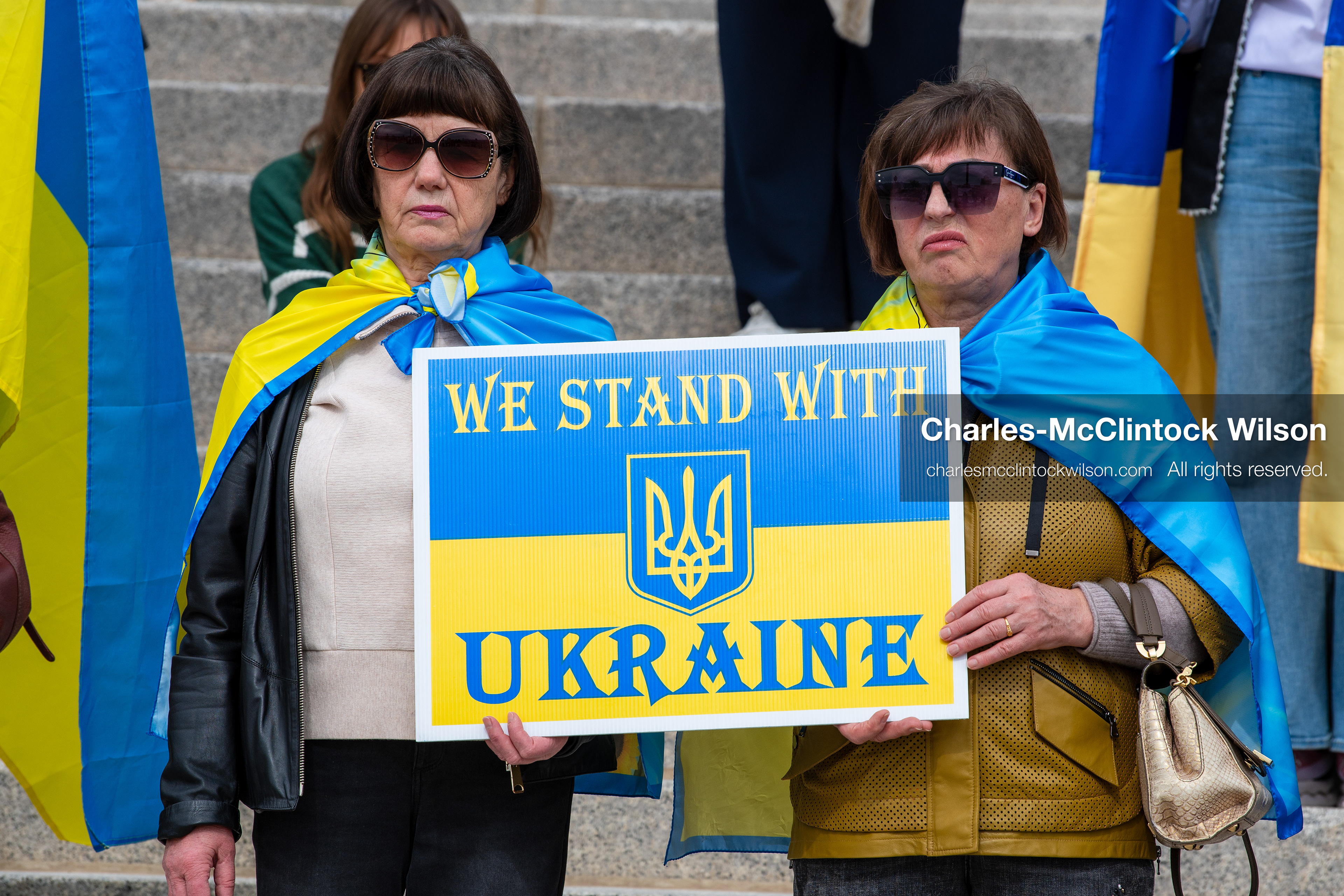 February 28, 2026, Salt Lake City, Utah, USA: Demonstrators hold signs reading We Stand With Ukraine while wrapped in the Ukrainian flag during the Stand With Ukraine rally at the Utah State Capitol. The gathering marked the four year anniversary of the full scale Russian invasion of Ukraine and brought community members together in support of Ukrainians and local humanitarian efforts. (Credit Image: © Charles McClintock Wilson/ZUMA Press Wire)