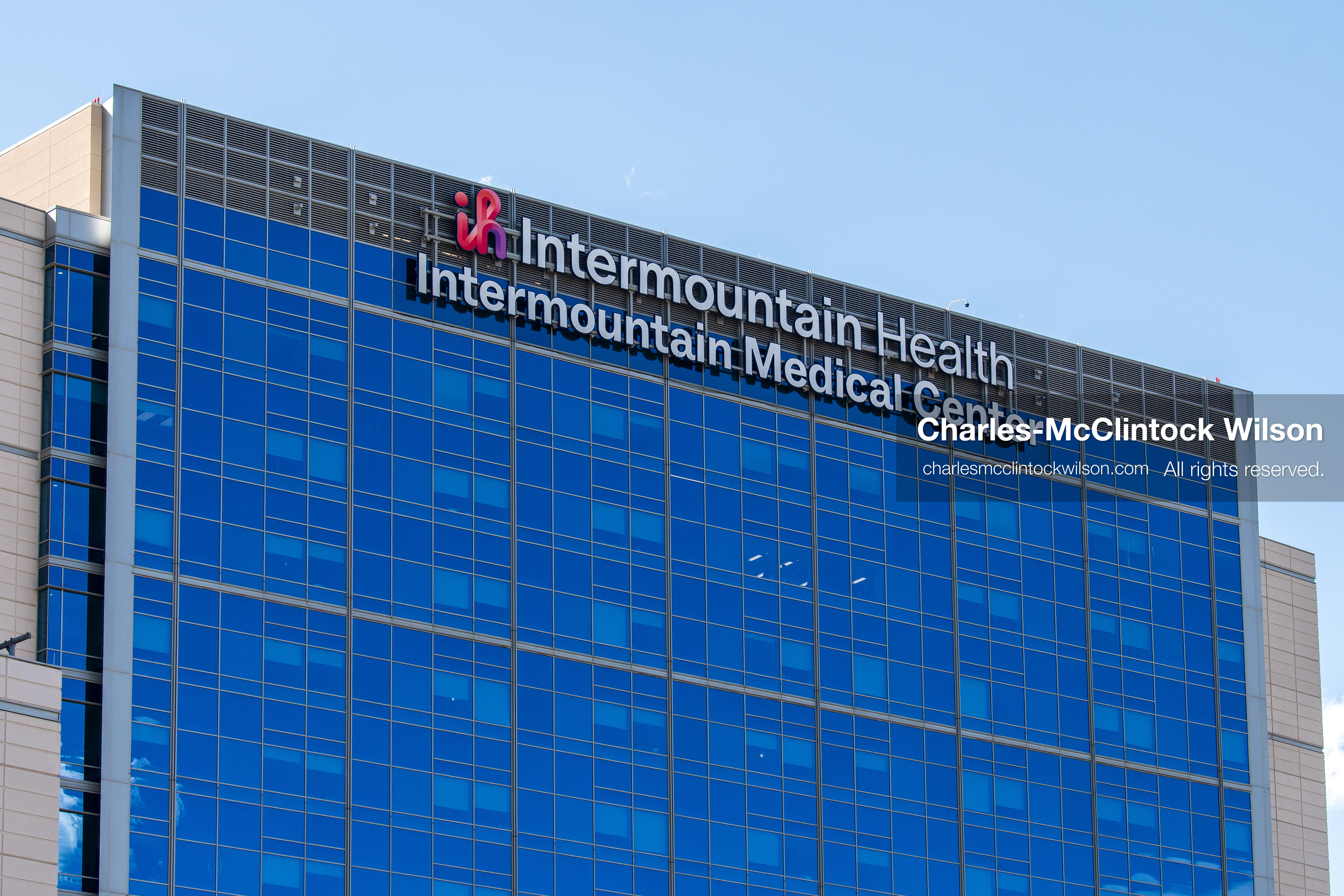 An exterior sign displaying the corporate logo is pictured on the glass facade of Intermountain Medical Center in Murray, Utah, United States, on August 17, 2026. Multiple regional police agencies secured the hospital perimeter as a safety precaution after shooting victims were admitted following a fatal shootout outside a funeral service in nearby Kearns. (Photo by Charles-McClintock Wilson/NurPhoto)