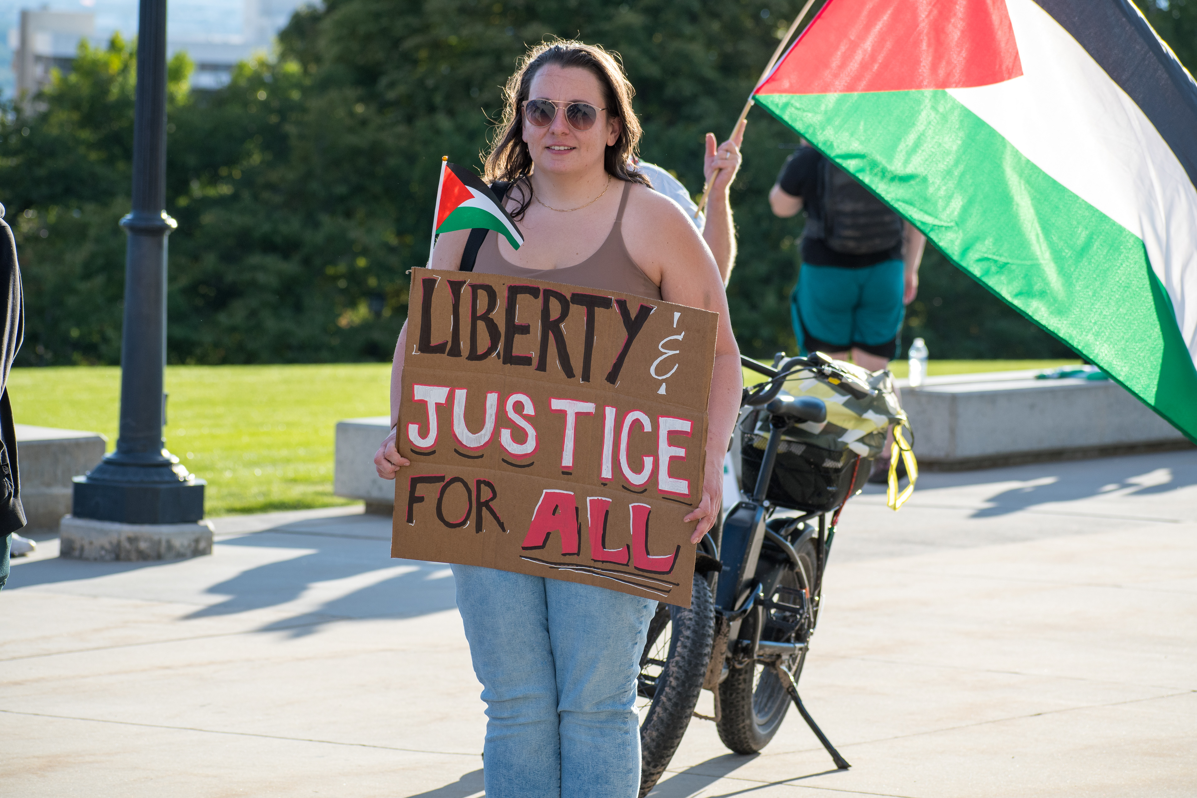 October 10, 2025, Salt Lake City, Utah, USA: A demonstrator holds a sign reading â€œLIBERTY & JUSTICE FOR ALLâ€ with a small Palestinian flag attached, during the Free Palestine Rally organized in front of the Utah State Capitol. Another participant displays a large Palestinian flag nearby. (Credit Image: © Charles-McClintock Wilson/ZUMA Press Wire)