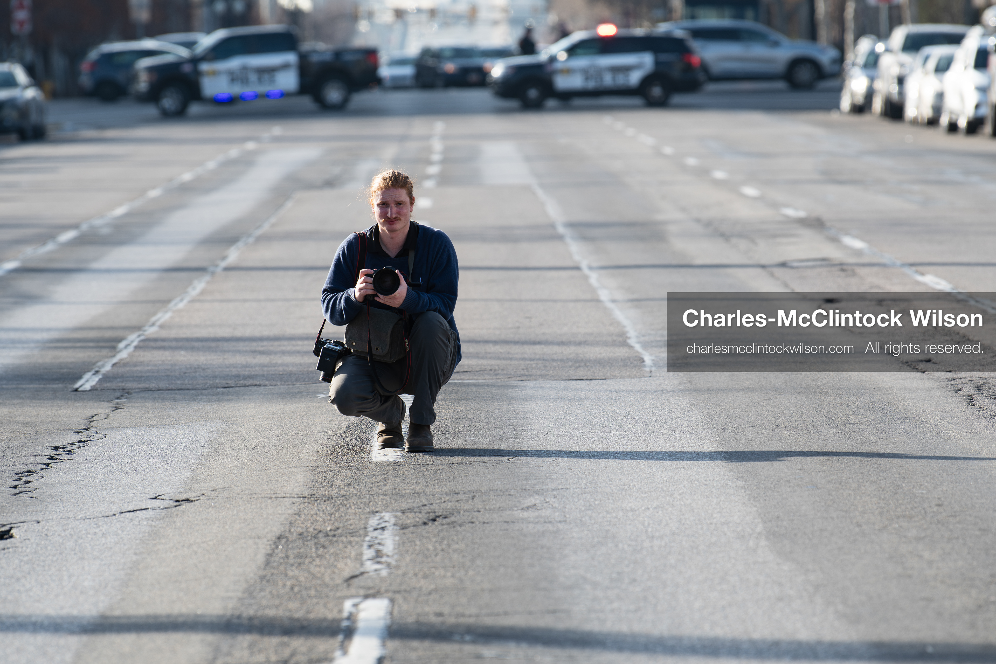 January 30, 2026, Salt Lake City, Utah, USA: A photographer crouches in the street as police vehicles block traffic during an anti‑ICE protest in Salt Lake City, part of a nationwide response to immigration enforcement policies. (Credit Image: © Charles‑McClintock Wilson/ZUMA Press Wire)
