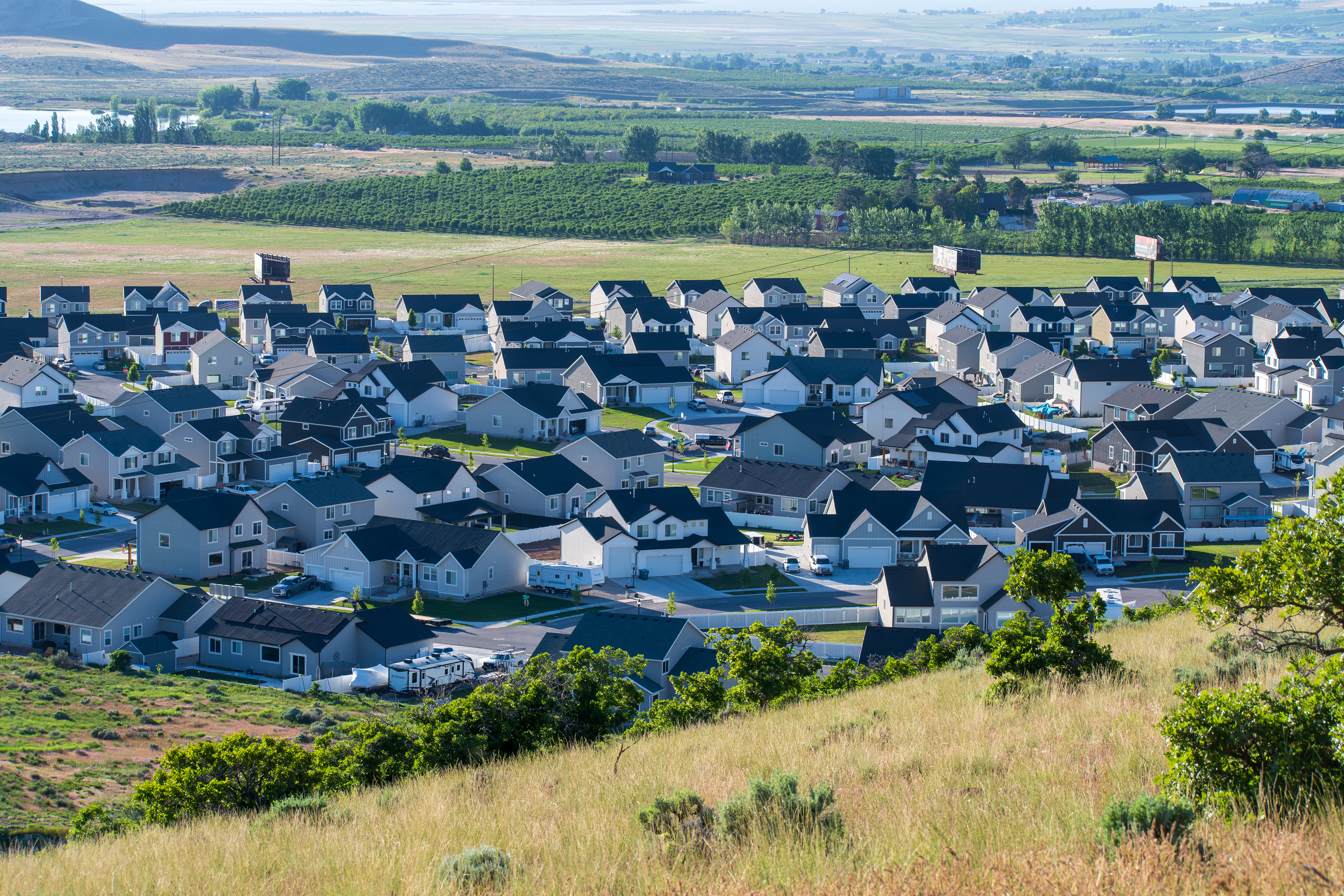 Santaquin, Utah – June 2, 2025: Wide view of a residential neighborhood with a mountainous backdrop and open valley under a clear sky.