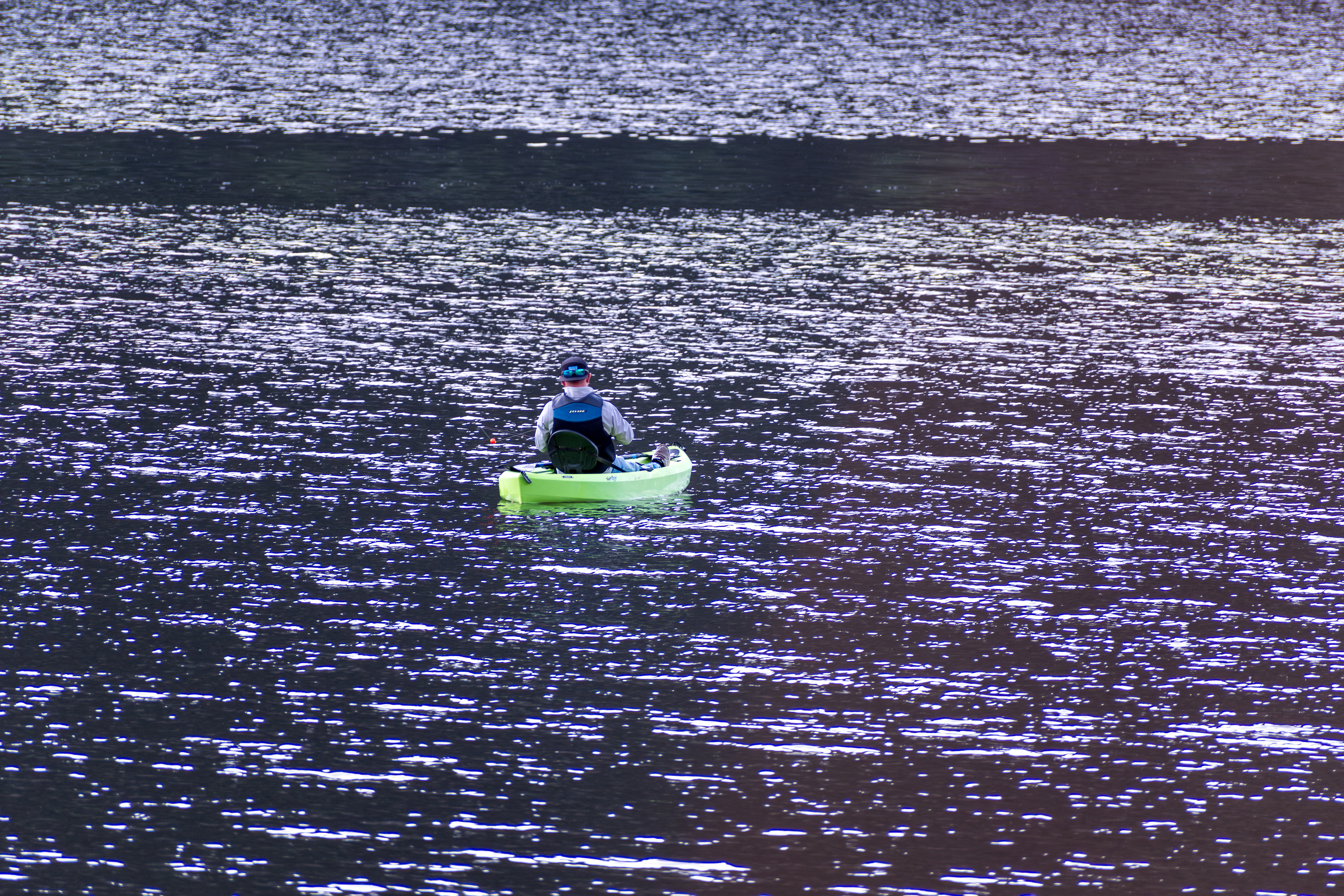 Summit County, Utah – July 20, 2025: A man paddles a bright green kayak while fishing at Smith and Morehouse Reservoir.