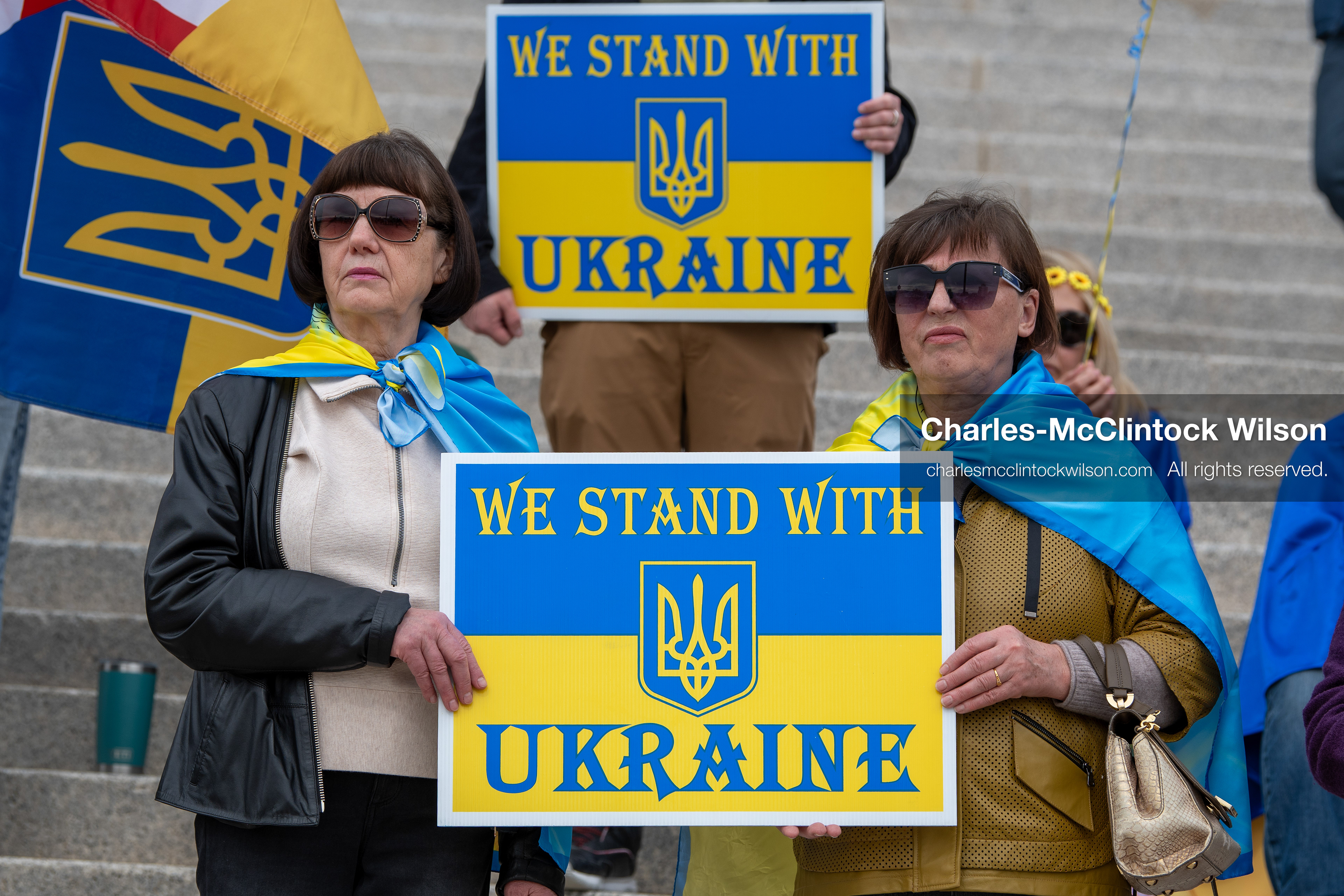  February 28, 2026, Salt Lake City, Utah, USA: Demonstrators hold signs reading We Stand With Ukraine while wrapped in the Ukrainian flag during the Stand With Ukraine rally at the Utah State Capitol. The gathering marked the four year anniversary of the full scale Russian invasion of Ukraine and brought community members together in support of Ukrainians and local humanitarian efforts. (Credit Image: © Charles McClintock Wilson/ZUMA Press Wire)