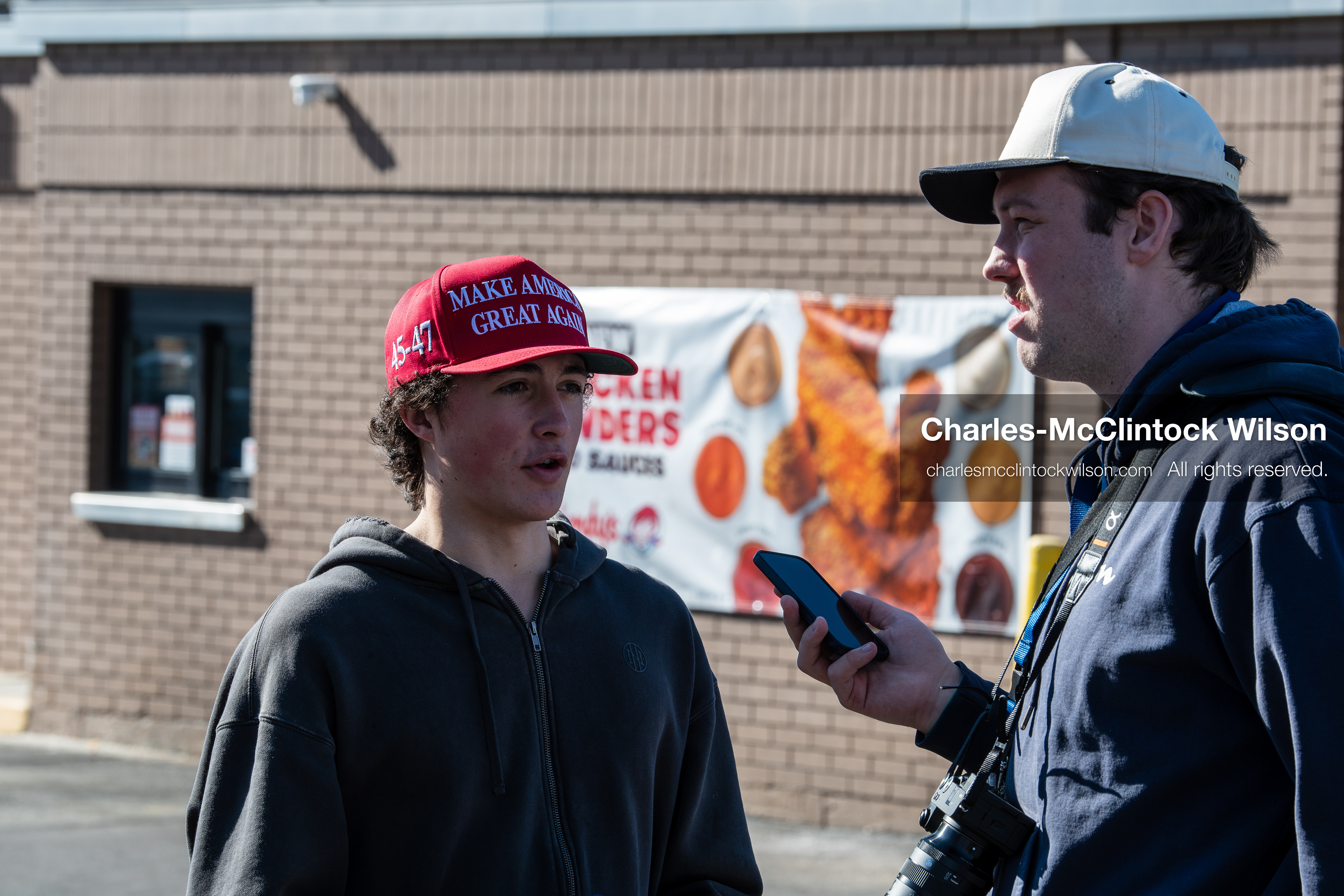 February 5, 2026, Provo, Utah, USA: A person wearing a red Make America Great Again hat is interviewed by another individual outside a business near Brigham Young University in Provo during a gathering opposing the presence of US Customs and Border Protection recruiters at a career fair held on the BYU campus. (Credit Image: © Charles McClintock Wilson/ZUMA Press Wire)