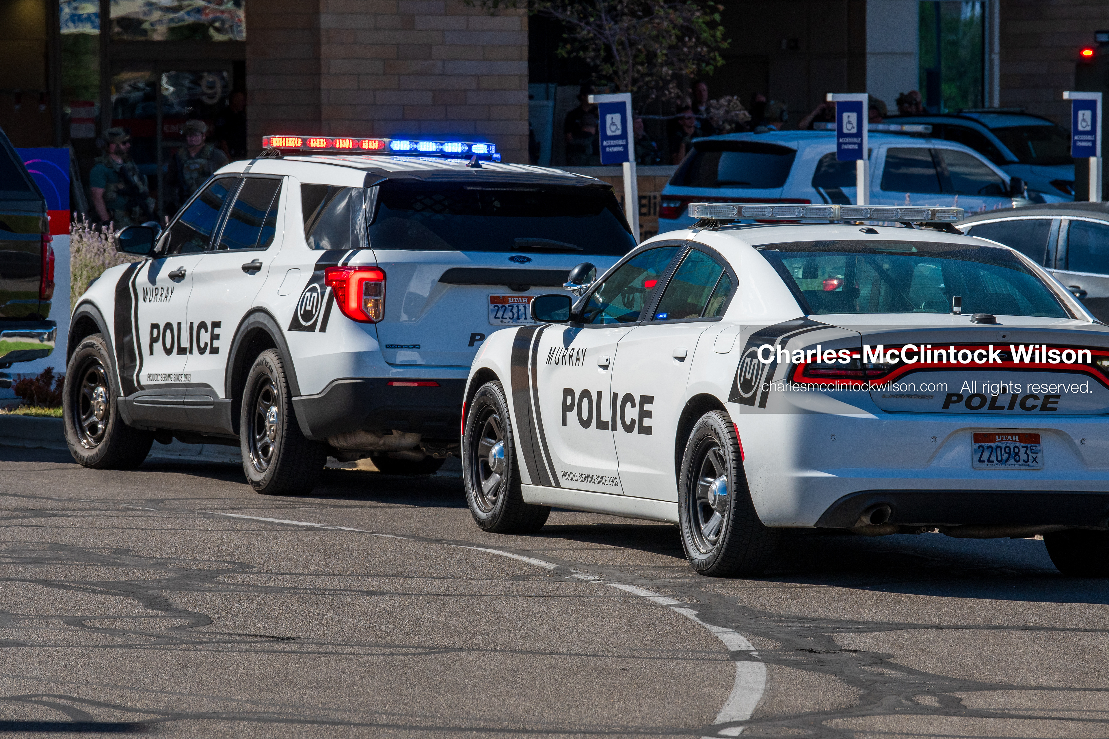 Marked police cruisers with their emergency lights flashing sit parked in a line outside the emergency room entrance at Intermountain Medical Center in Murray, Utah, United States, on August 17, 2026. Multiple regional police agencies secured the hospital perimeter as a safety precaution after shooting victims were admitted following a fatal shootout outside a funeral service in nearby Kearns. (Photo by Charles-McClintock Wilson/NurPhoto)