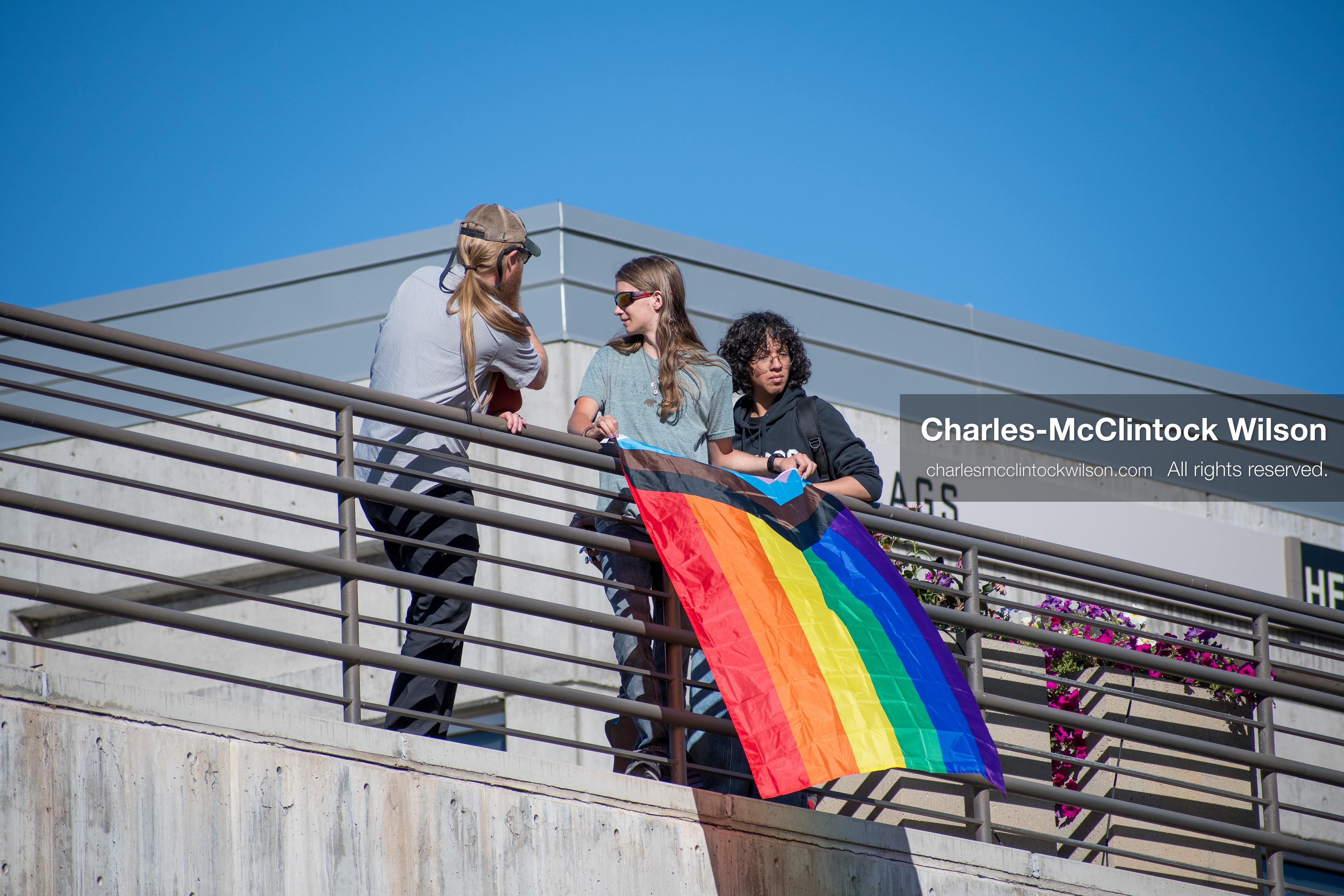 September 10, 2025, Orem, Utah, USA: A group of individuals stand atop the Fountain Courtyard at Utah Valley University, holding a Progress Pride flag during conservative activist Charlie Kirk’s American Comeback Tour appearance. The event drew over 3,000 attendees and was marked by heightened civic tension and symbolic gestures from both supporters and critics. Kirk was fatally shot moments later during the public Q&A session, prompting national scrutiny of campus security protocols and institutional response. (Credit Image: © Charles‑McClintock Wilson/ZUMA Press Wire)
