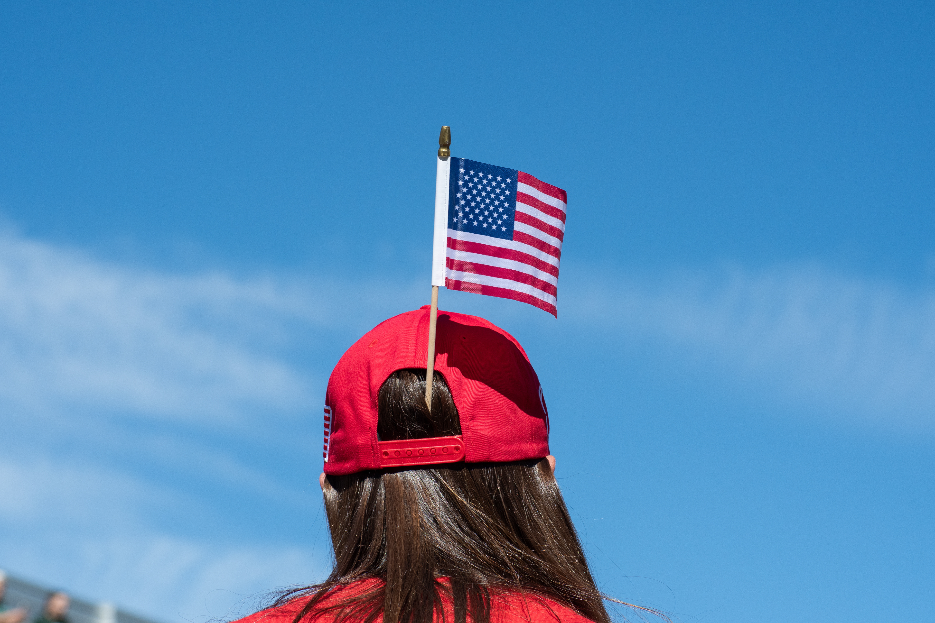OREM, UTAH – SEPTEMBER 10, 2025: An attendee stands near the event perimeter at Utah Valley University during the opening stop of the American Comeback Tour. Dressed in red and framed against a clear sky, the individual reflects a moment of personal expression and quiet anticipation. The image captures the symbolic texture and civic presence that shaped the atmosphere of the day. © Charles-McClintock Wilson / ZUMA Press