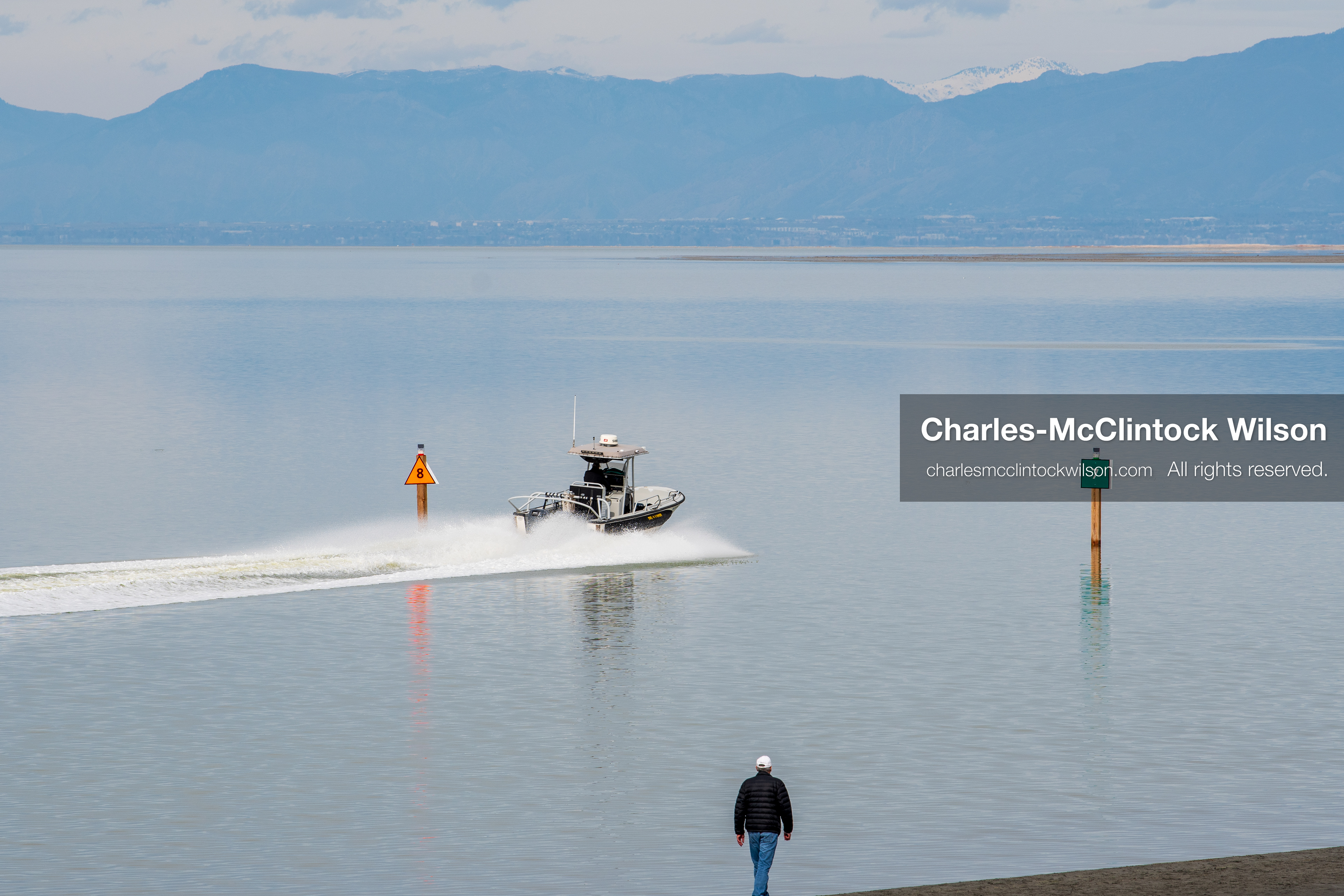 March 1, 2026, Great Salt Lake, Utah, USA: A person stands along the shoreline of the Great Salt Lake while a boat moves through a marked channel as water levels in the region remain historically low. Reports from state officials and the Great Salt Lake Strike Team state that the lake continues to fall within a serious adverse‑effects range, with elevations among the lowest recorded in more than one hundred years. The lake has drawn increased public attention as lawmakers consider large‑scale water projects and long‑term plans to address declining conditions. (Credit Image: © Charles‑McClintock Wilson/ZUMA Press Wire)