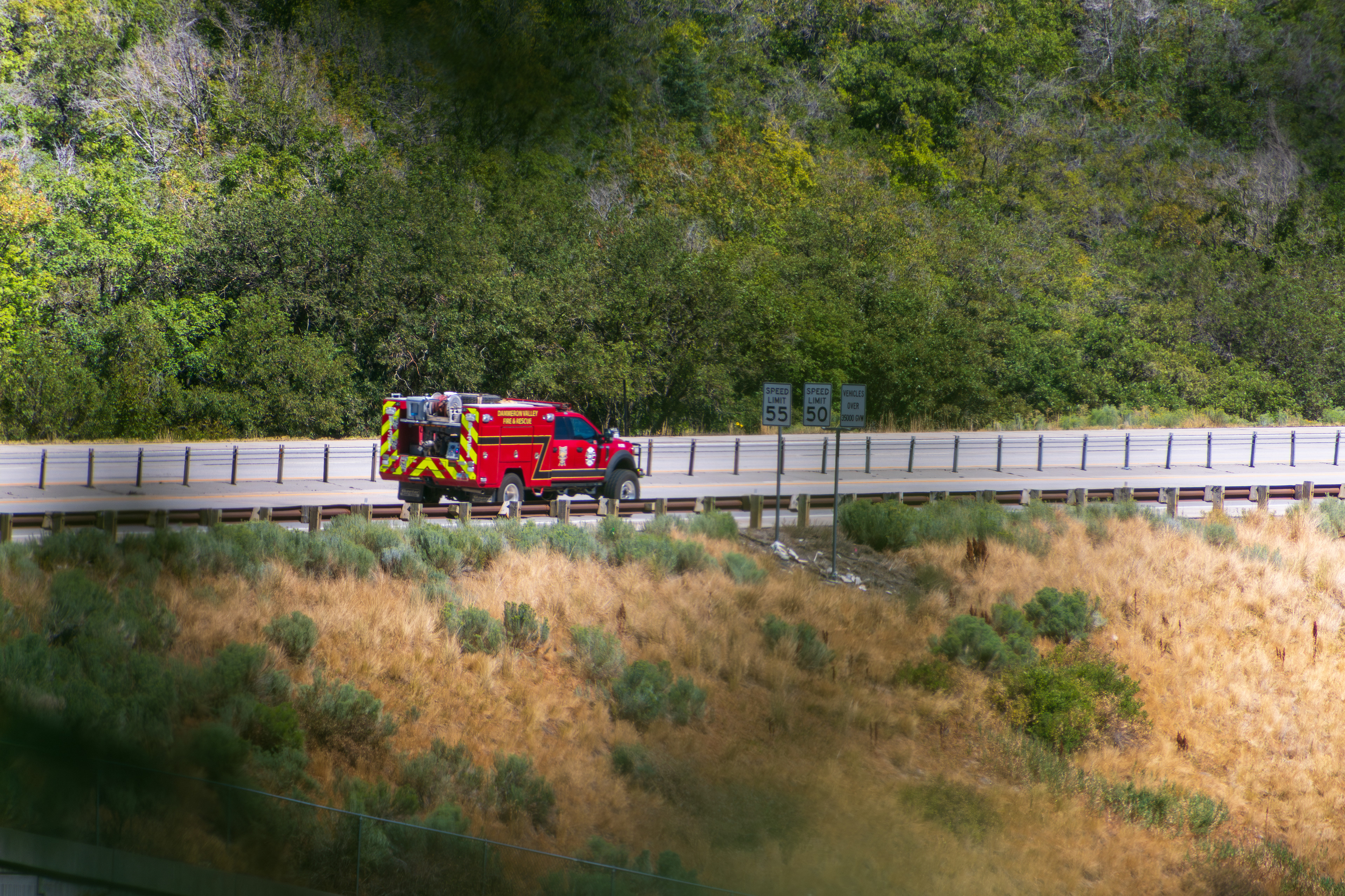 Provo Canyon, Utah, USA — September 1, 2025: A red fire truck travels along an elevated road bordered by trees and grassy terrain near Bridal Veil Falls in Provo Canyon, Utah.