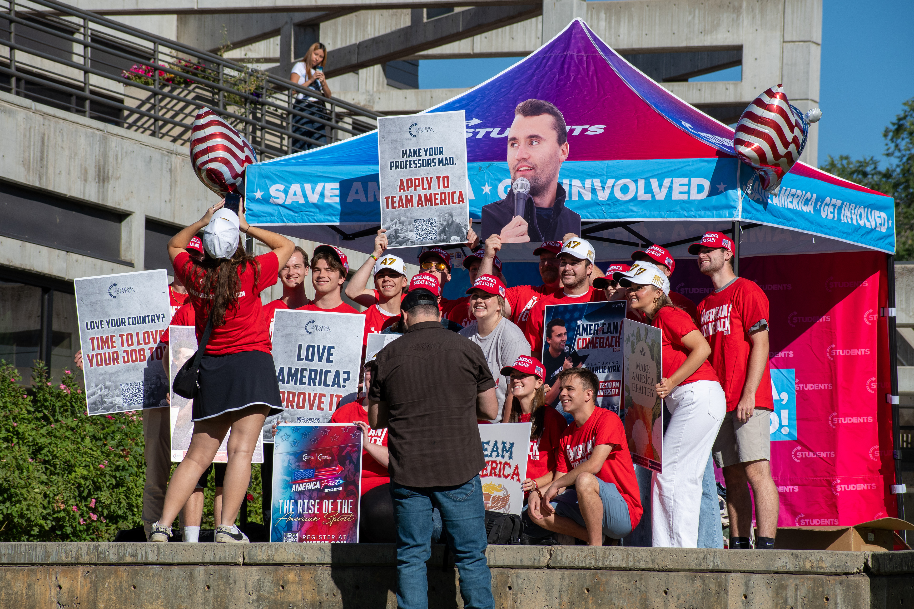 OREM, UTAH – SEPTEMBER 10, 2025: Attendees gather outside the Pope Science building at Utah Valley University during the opening stop of the American Comeback Tour. Surrounded by signage and coordinated attire, the group reflects a moment of thematic clarity, civic invitation, and communal energy. The image captures the rhythm of participation and the visual texture that shaped the event’s atmosphere. © Charles-McClintock Wilson / ZUMA Press