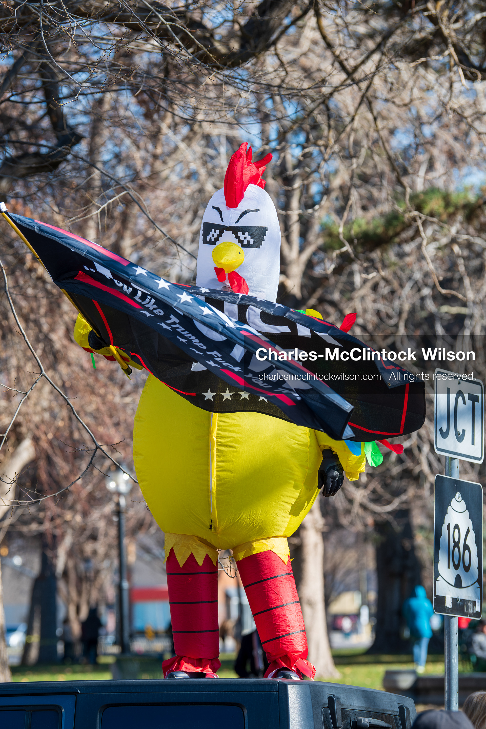 Salt Lake City, Utah, January 10, 2026: A person wearing a chicken costume stands on top of a vehicle during the ICE Out for Good protest at Washington Square Park, holding two flags with anti‑ICE and anti‑Trump messaging. (Credit Image: © Charles‑McClintock Wilson/ZUMA Press Wire)