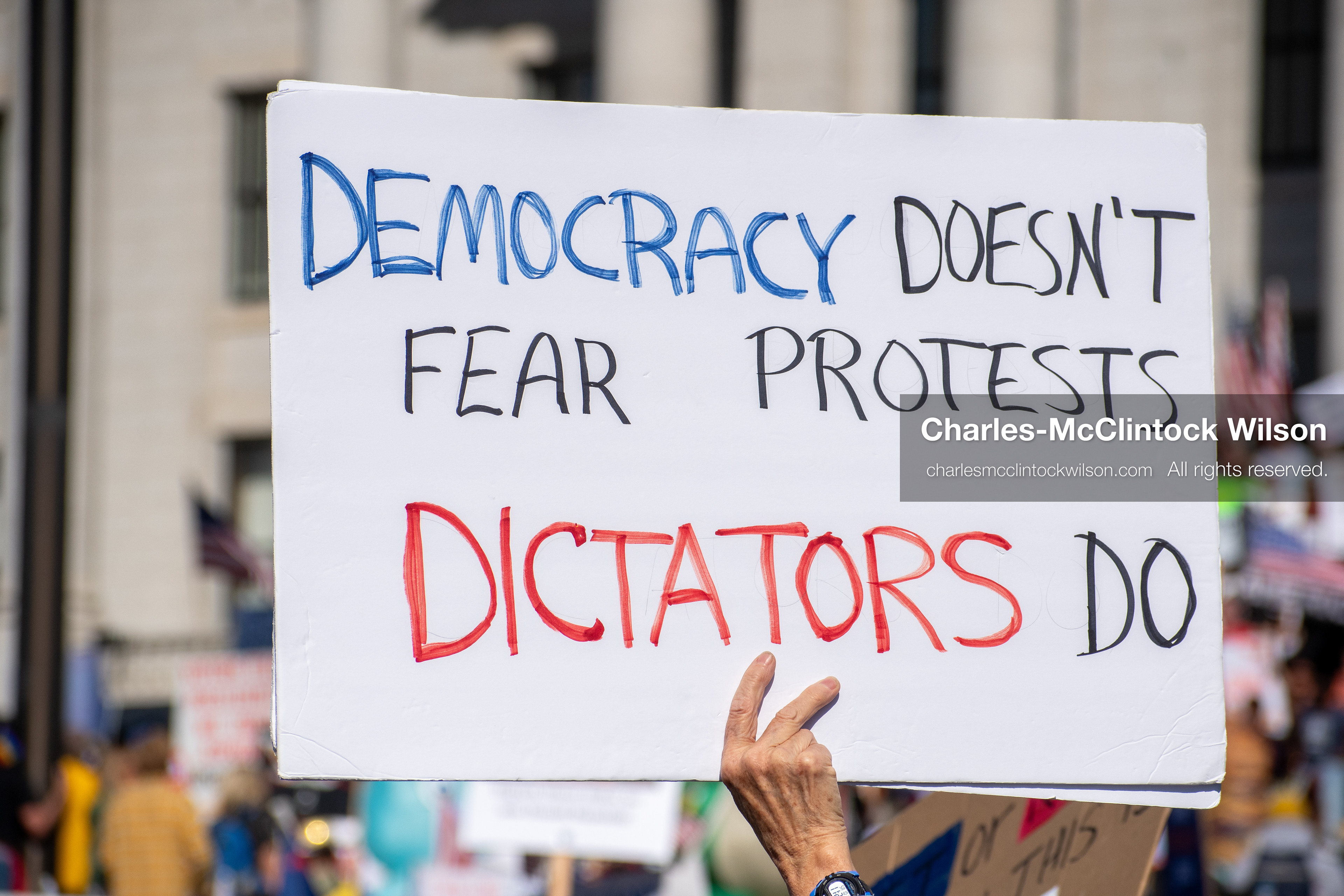 October 18, 2025, Salt Lake City, Utah, USA: A demonstrator raises a placard during a "No Kings" protest held at the Utah State Capitol. Other participants and signs are visible in the background during the public gathering.