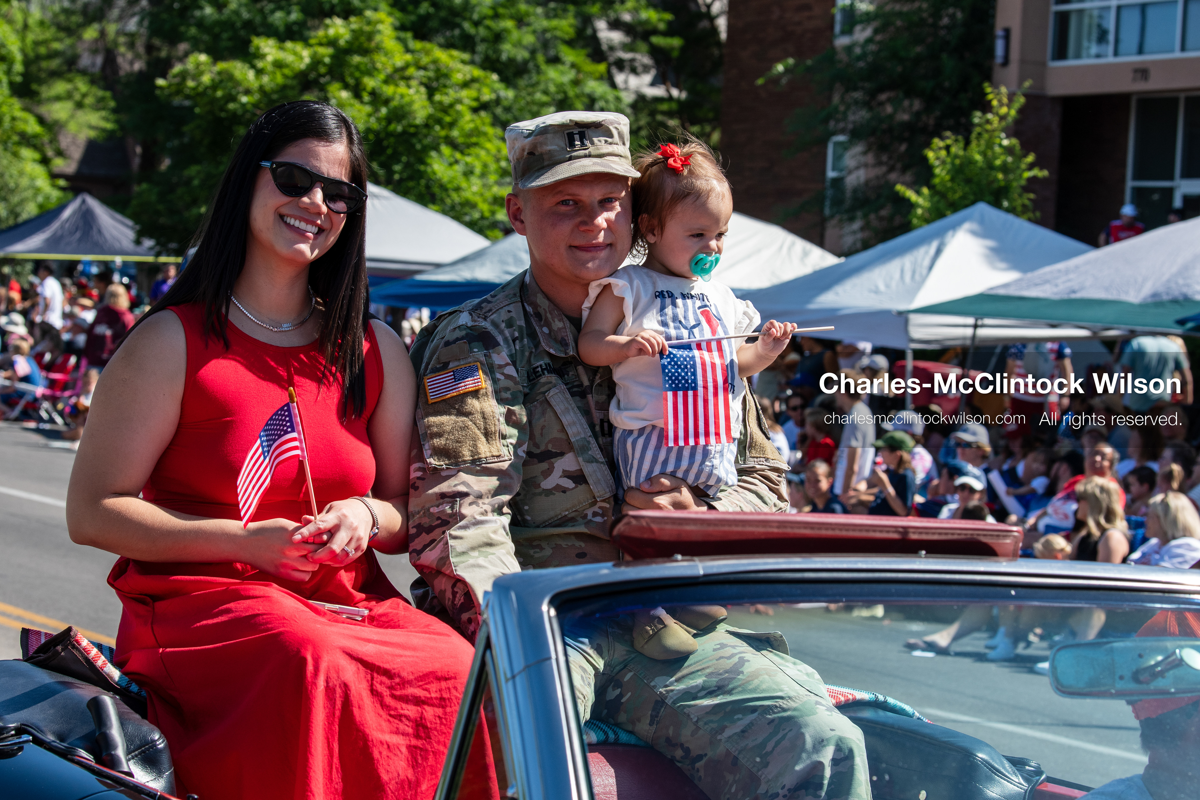 July 4, 2026, Provo, Utah, USA: A military service member in uniform holds a child beside a woman in a red dress as they ride in a convertible during America's Freedom Festival Grand Parade in Provo, Utah, Saturday, July 4, 2026. The annual Independence Day event features expanded programming to honor the 250th anniversary of United States independence. (Credit Image: © Charles-McClintock Wilson/ZUMA Press Wire)