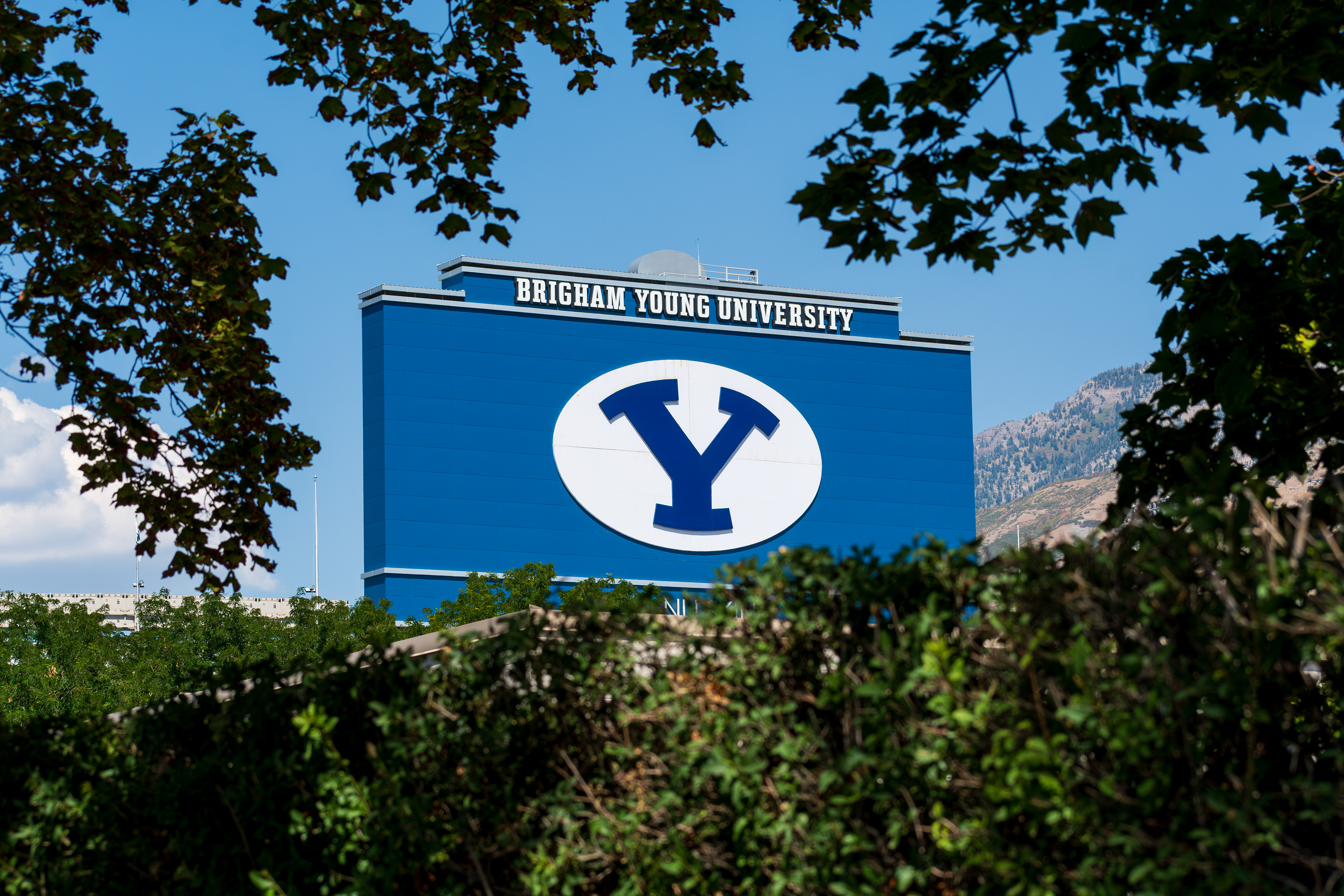 Provo, Utah – September 1, 2025: Brigham Young University’s iconic “Y” signage is seen on a campus building, framed by foliage and the Wasatch Range.