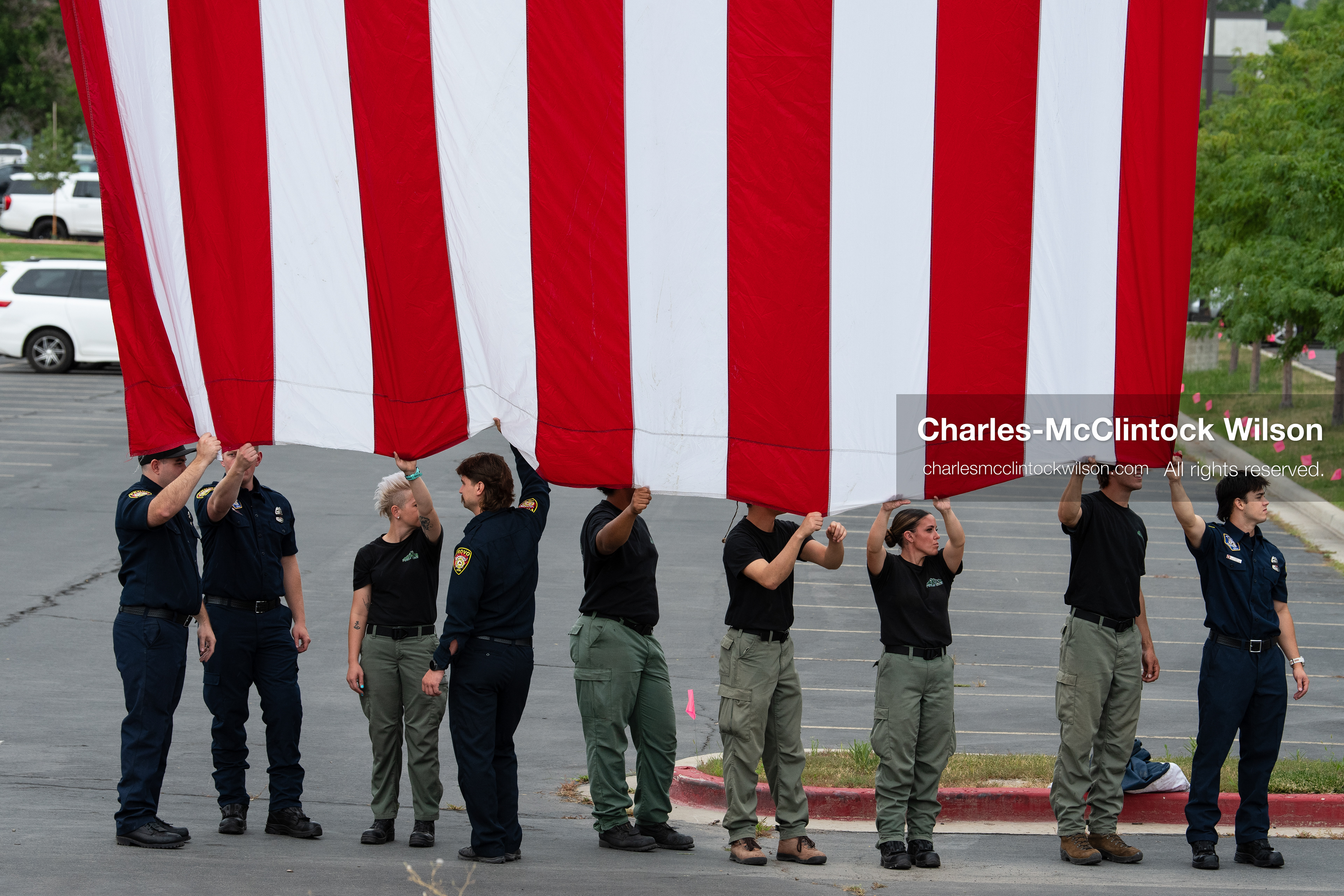 First responders stand in a row holding the bottom edge of a large American flag outside the UCCU Center at Utah Valley University in Orem, Utah, on Wednesday, July 29, 2026. More than 300 people came to the public memorial ceremony to honor Provo Fire Captain Spencer Long, his wife Katrina, and three of their sons, who died after a flash flood hit their campsite near the Sunglow Campground in Wayne County. (Photo by Charles-McClintock Wilson/Sipa USA)