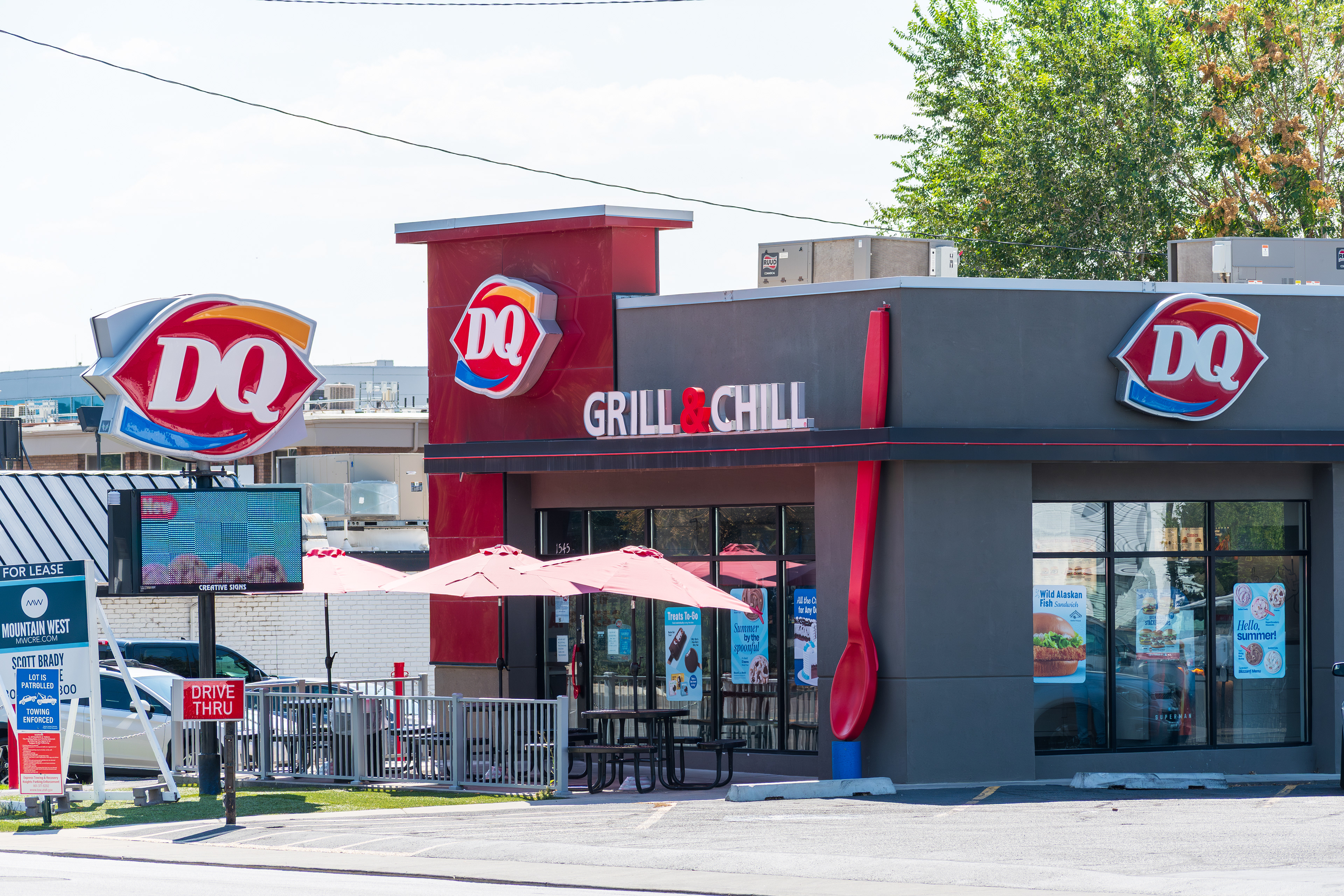 Provo, Utah, USA — September 1, 2025: A Dairy Queen Grill and Chill restaurant features outdoor seating with red umbrellas and a modern exterior design.
