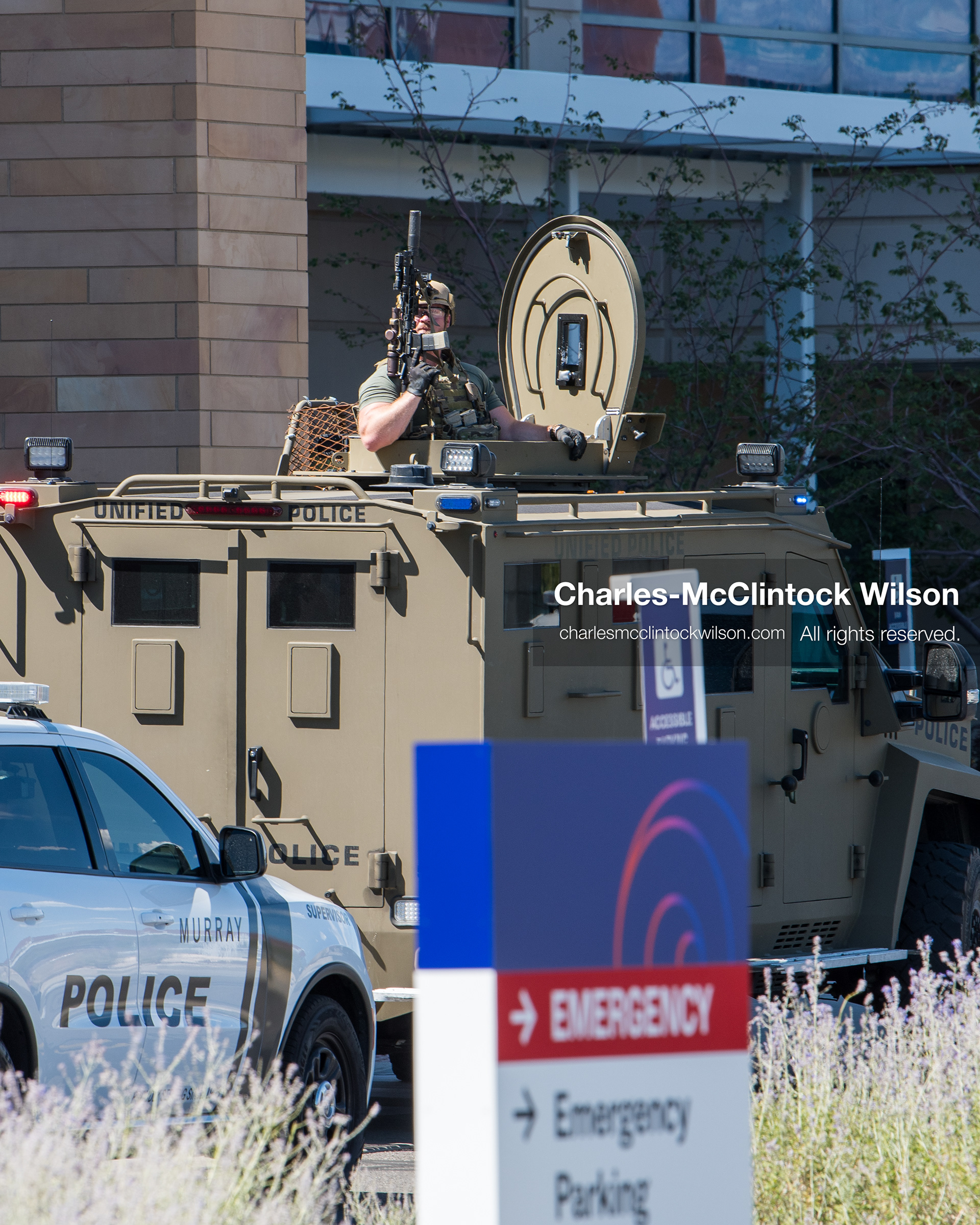 An armed law enforcement officer stands inside the roof turret hatch of an armored tactical vehicle outside Intermountain Medical Center in Murray, Utah, on Monday, August 17, 2026. Multiple regional law enforcement agencies converged to heavily secure the hospital perimeter as a safety precaution after shooting victims arrived from a fatal shootout that erupted outside a funeral service in nearby Kearns earlier that day. (Photo by Charles-McClintock Wilson/Sipa USA)