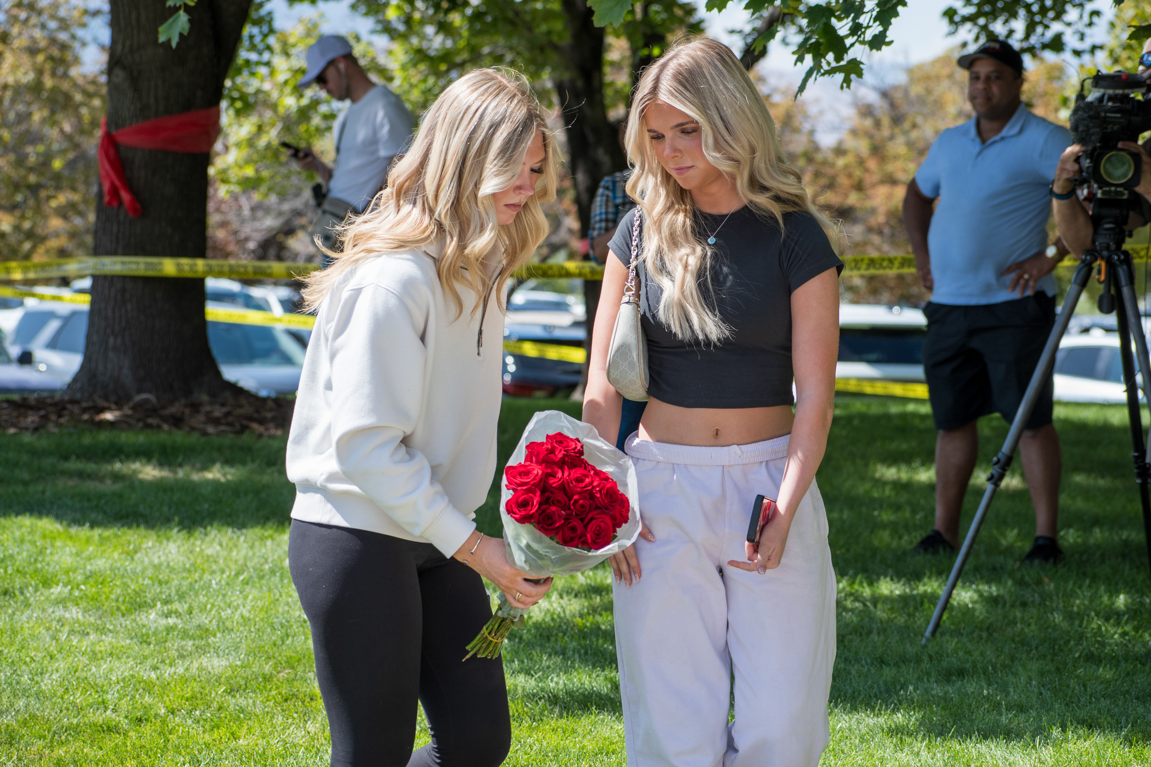 OREM, UTAH – SEPTEMBER 12, 2025: Two individuals stand at a memorial site for Charlie Kirk near Utah Valley University, one holding a bouquet of red roses. In the background, others gather and document the scene as part of a tribute event. © Charles‑McClintock Wilson / ZUMA Press