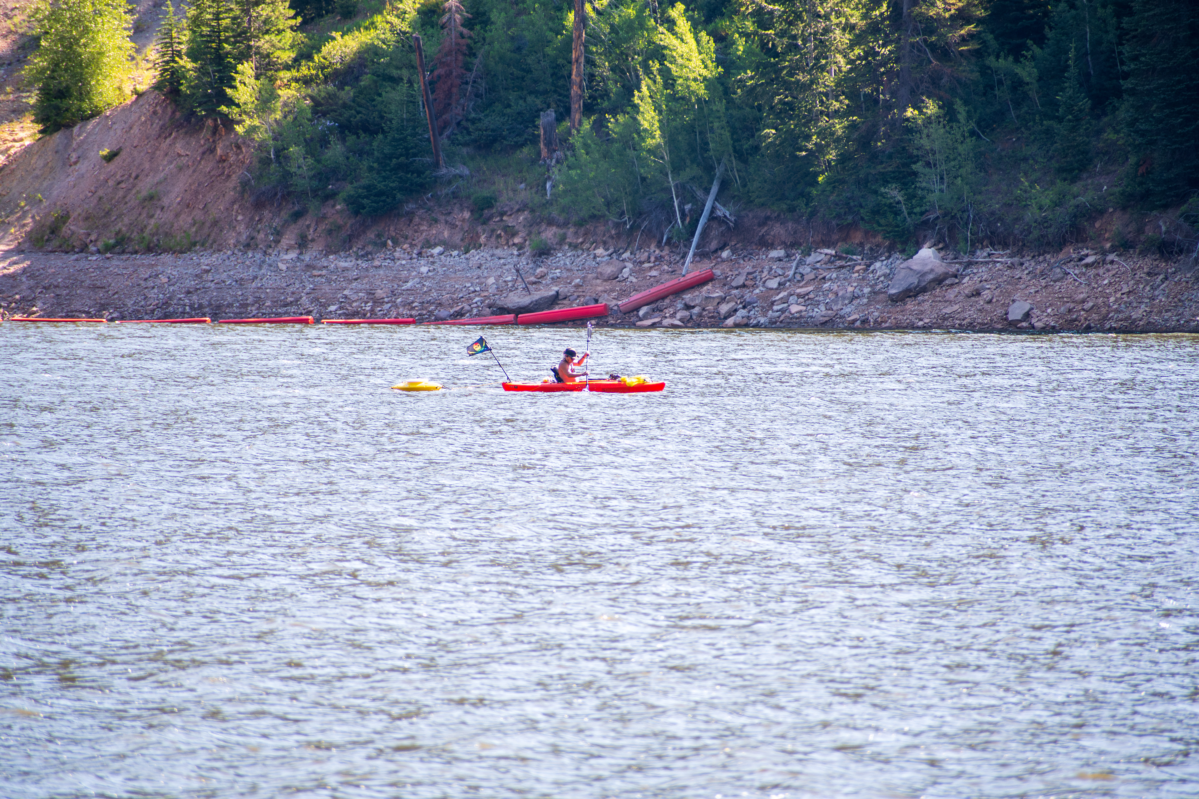 Summit County, Utah – July 20, 2025: A man paddles a bright orange kayak at Smith and Morehouse Reservoir.