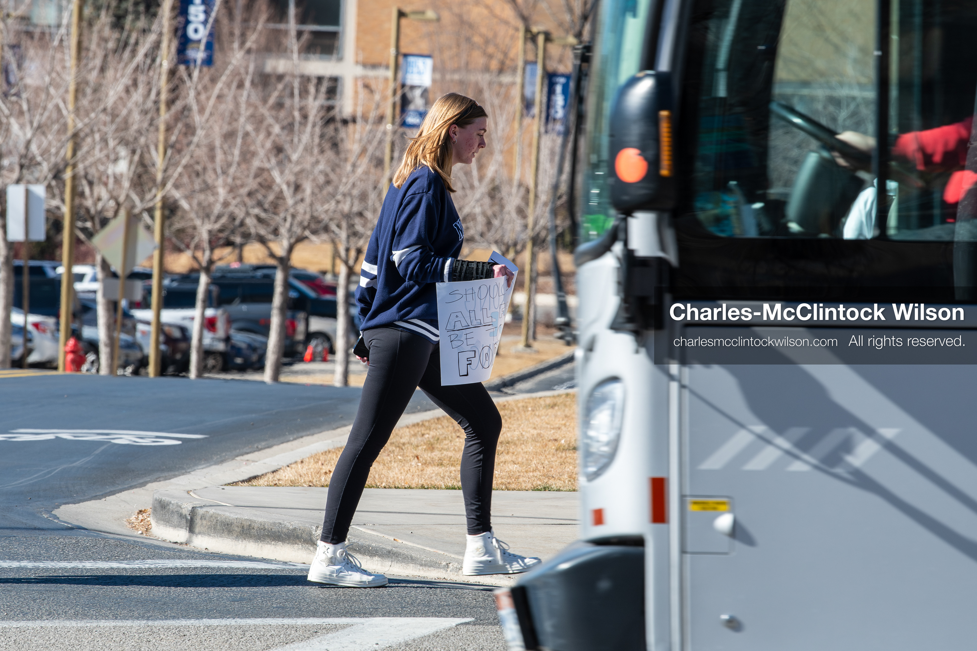 February 5, 2026, Provo, Utah, USA: A person carrying a protest sign walks past a bus near Brigham Young University in Provo during a protest opposing the presence of US Customs and Border Protection recruiters at a career fair held at the university. (Credit Image: © Charles McClintock Wilson/ZUMA Press Wire)