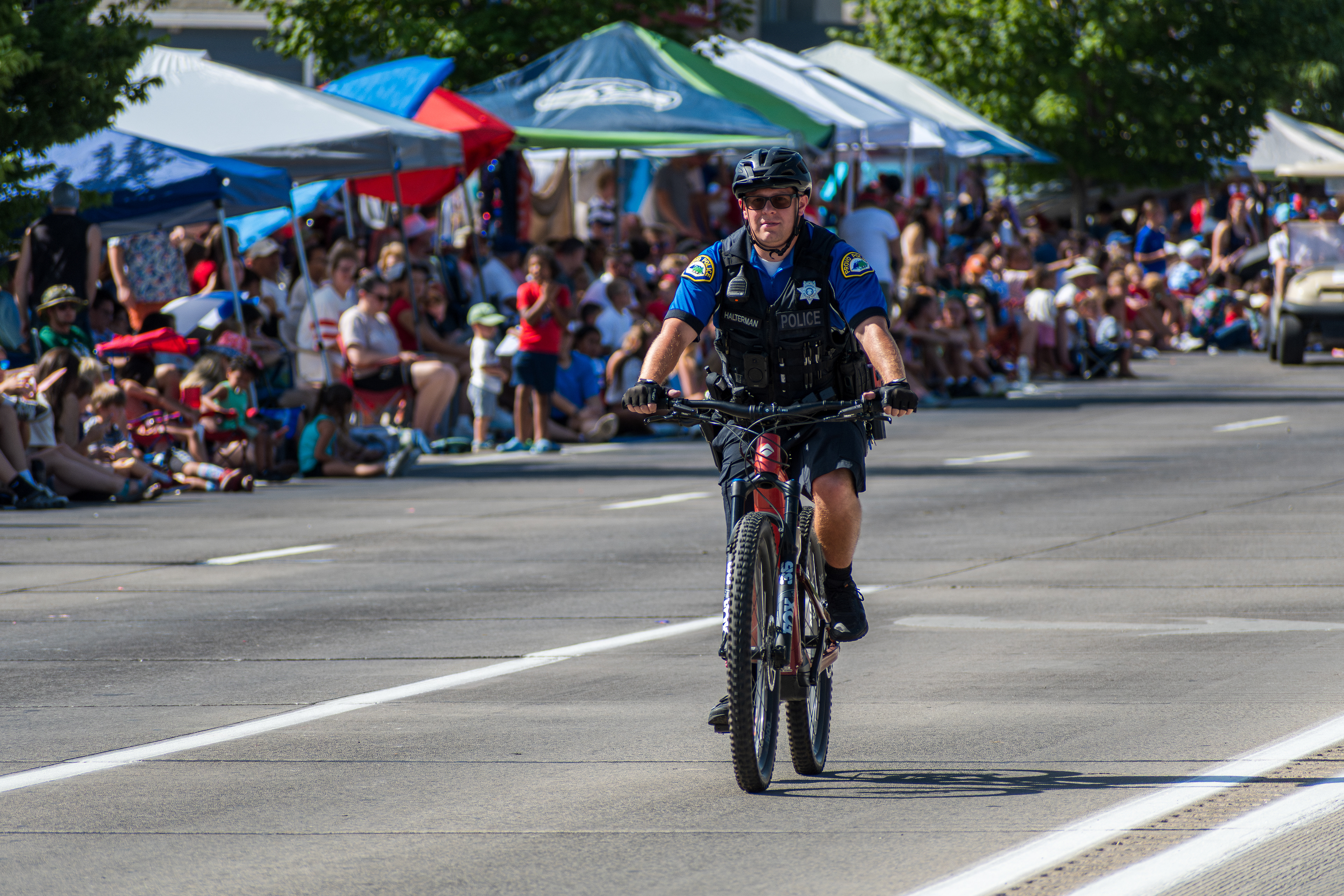 Provo, Utah – July 4, 2025: A police officer rides a bicycle along the parade route during the Freedom Festival Grand Parade, providing security and engaging with the community.