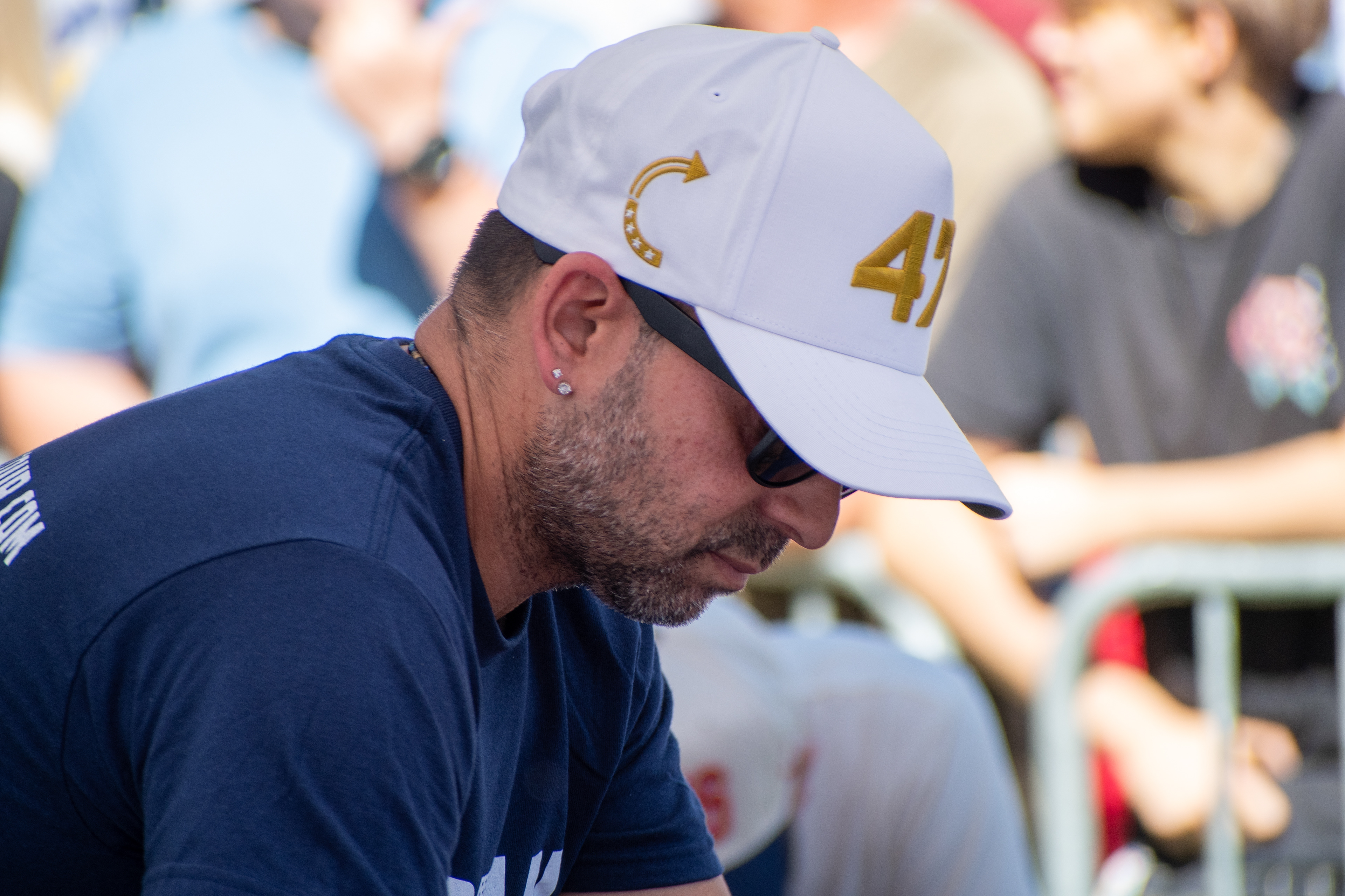 OREM, UTAH – SEPTEMBER 10, 2025: An attendee sits near the barricades at Utah Valley University during the opening stop of the American Comeback Tour. Wearing a white cap marked “41” and a navy shirt, the individual reflects a moment of quiet observation and personal presence. The image captures the symbolic styling and emotional stillness within the rhythm of a public gathering. © Charles-McClintock Wilson / ZUMA Press